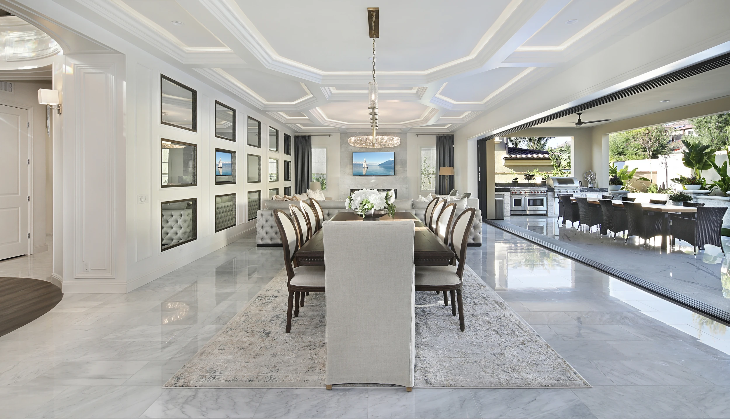 Open dining and living room with pale tufted seating and white kitchen