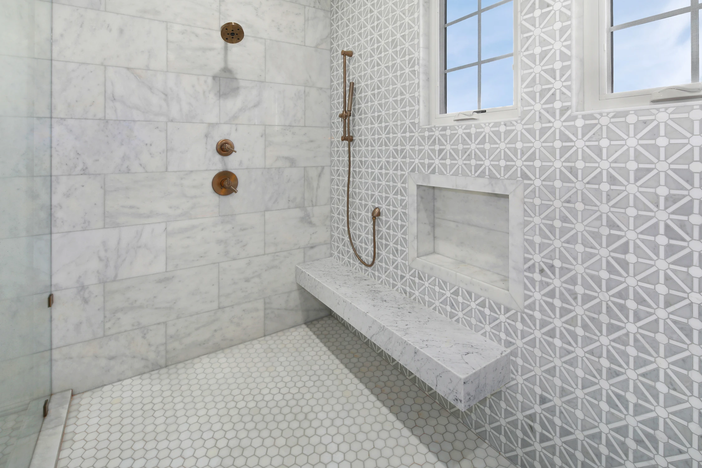 Walk-in shower with white tile, bench, and patterned accent wall