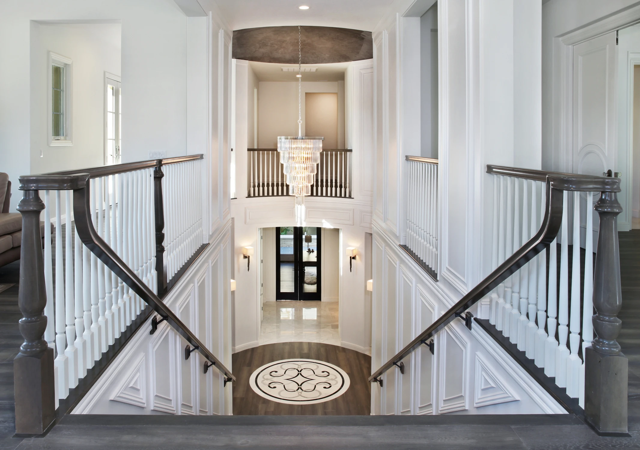 Upper staircase with dark railings and chandelier below