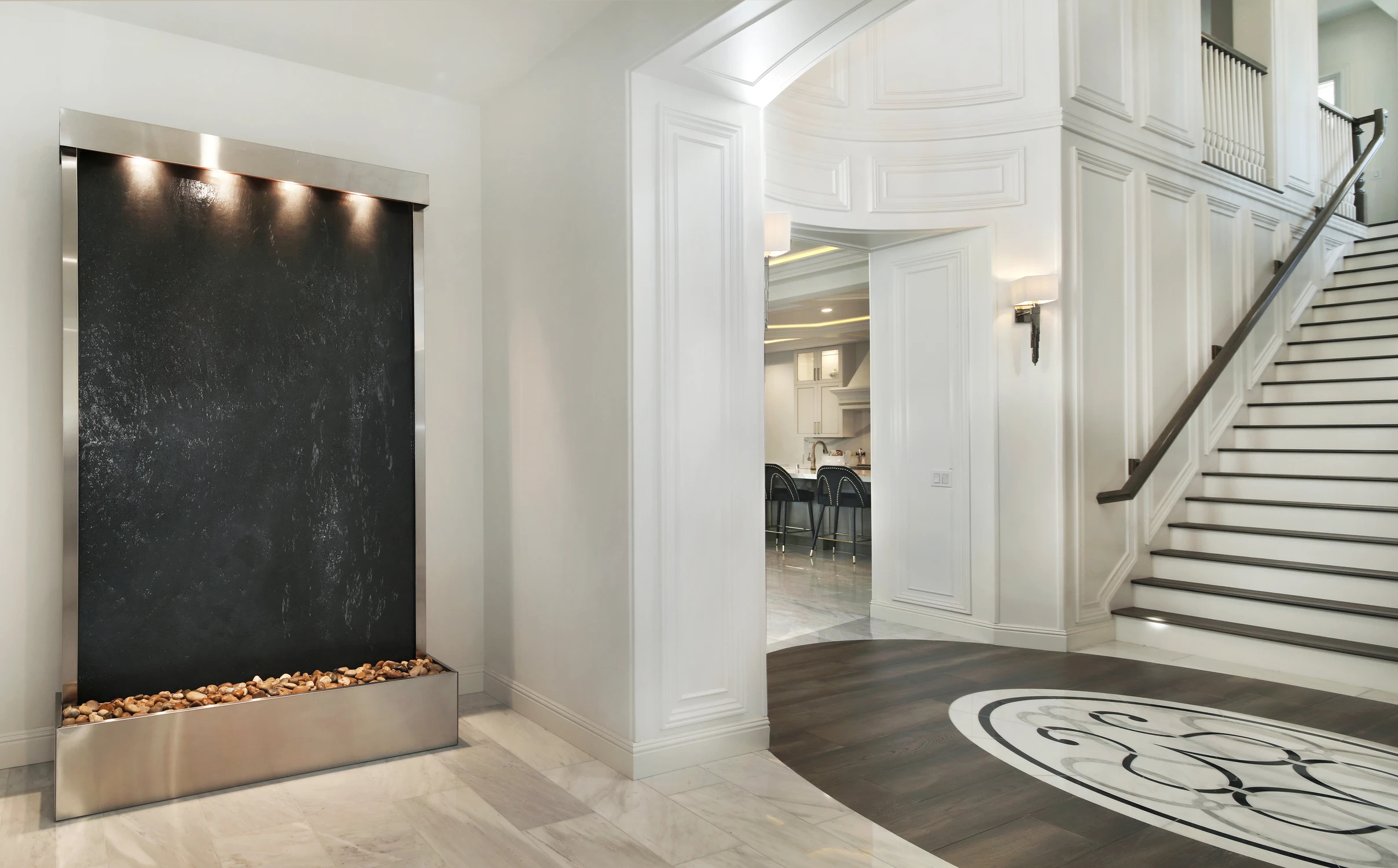 Dark stone water feature beside white staircase