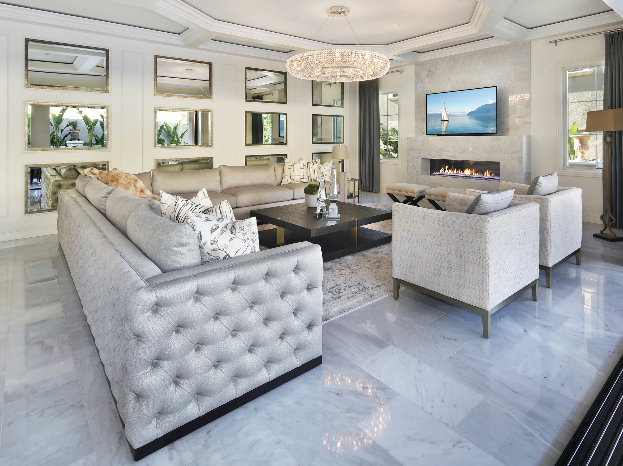 Living room with tufted sofas, mirrored wall, and marble fireplace