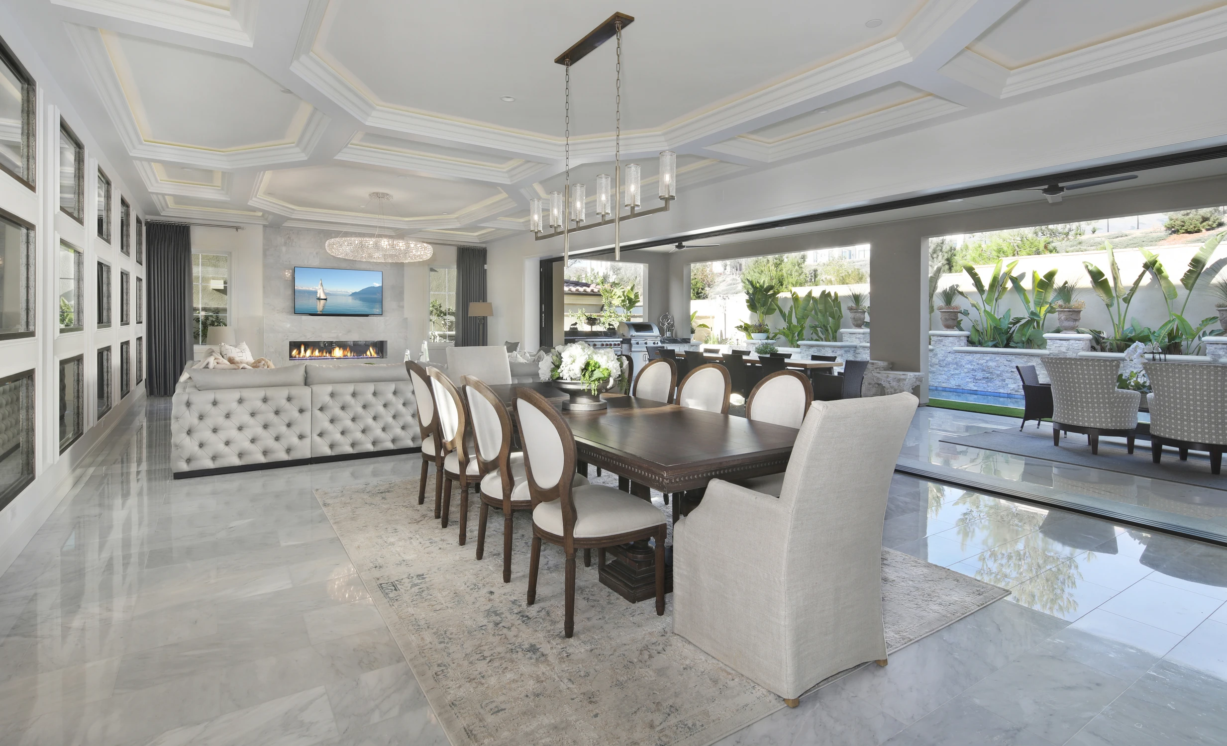 Open dining and living room with pale seating and black-framed windows