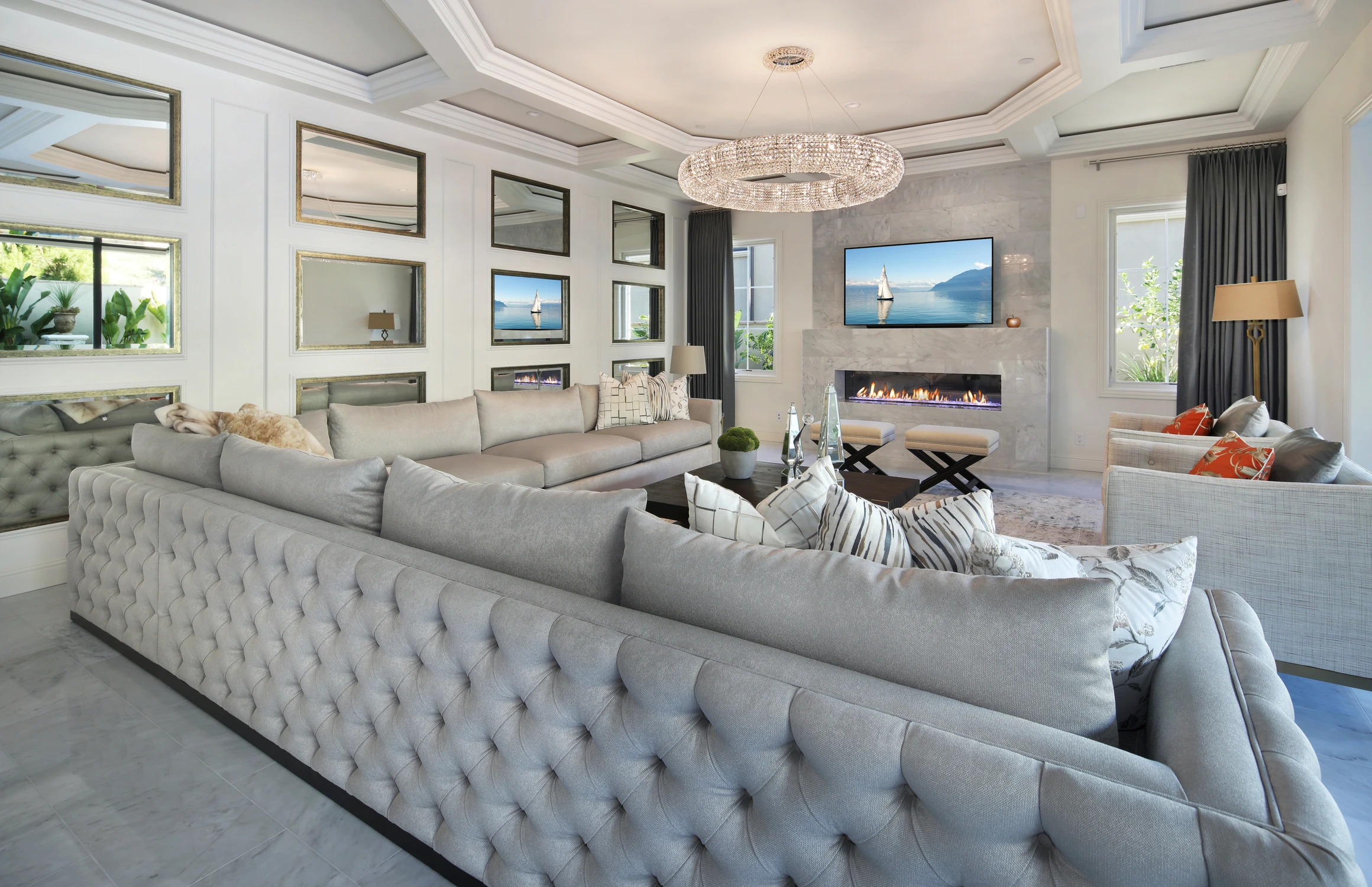 Living room with tufted gray sofa, crystal chandelier, and fireplace