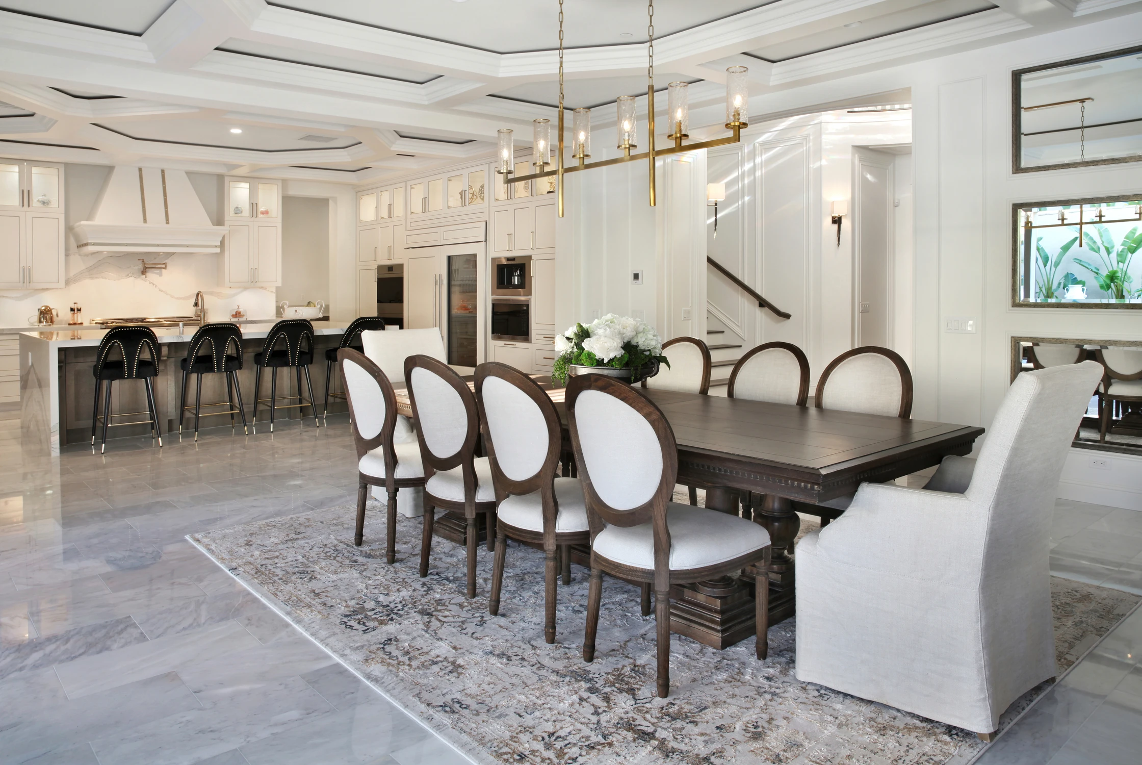 Dining room with white upholstered chairs and open kitchen