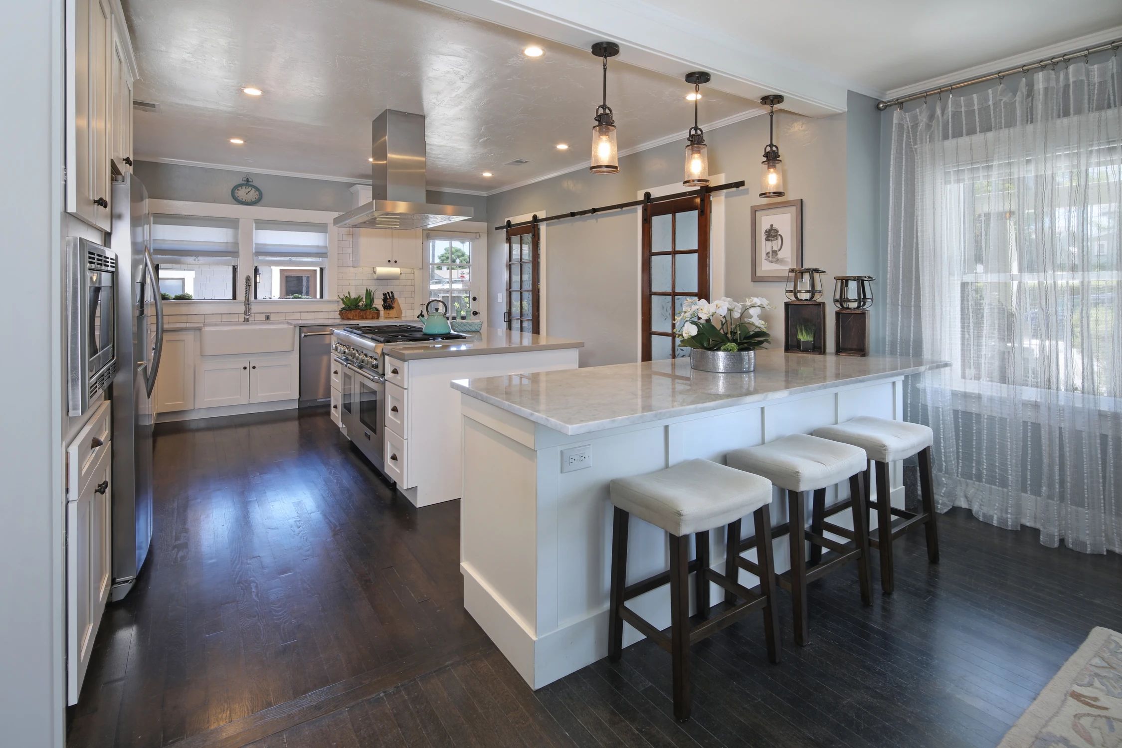 Bright white kitchen with marble island and pendant lights