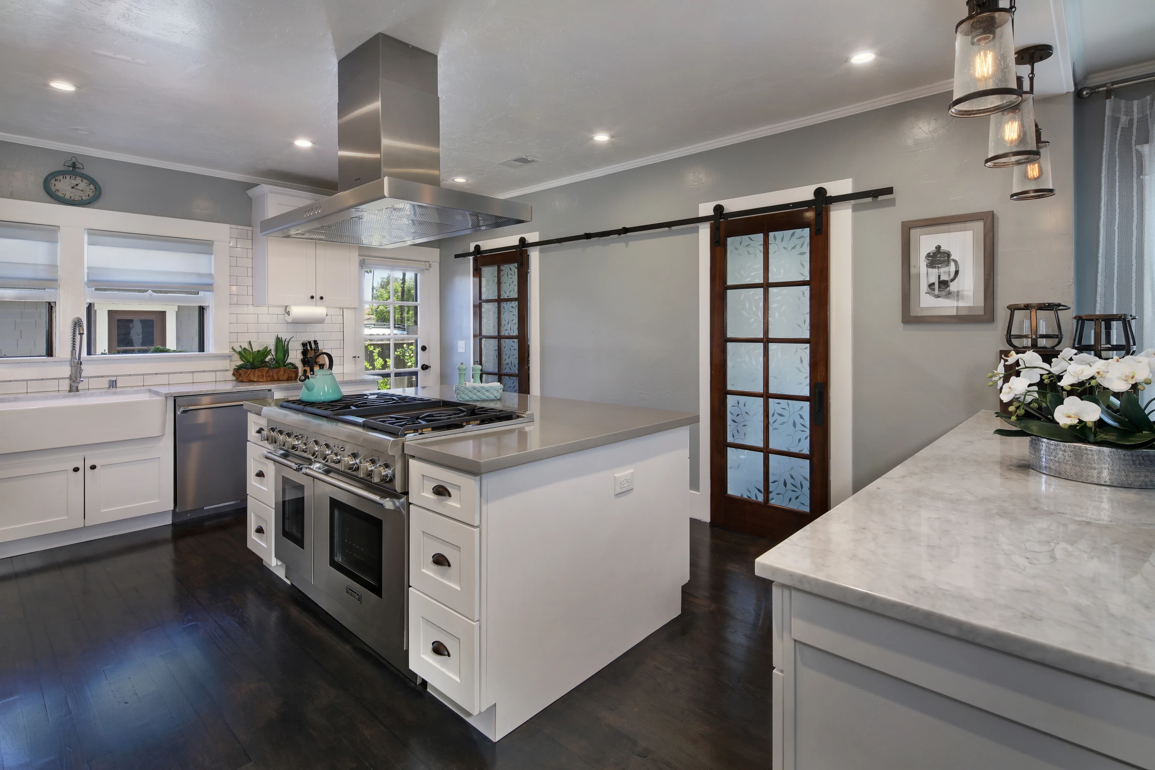 Kitchen island with gas range, marble counters, and frosted glass doors