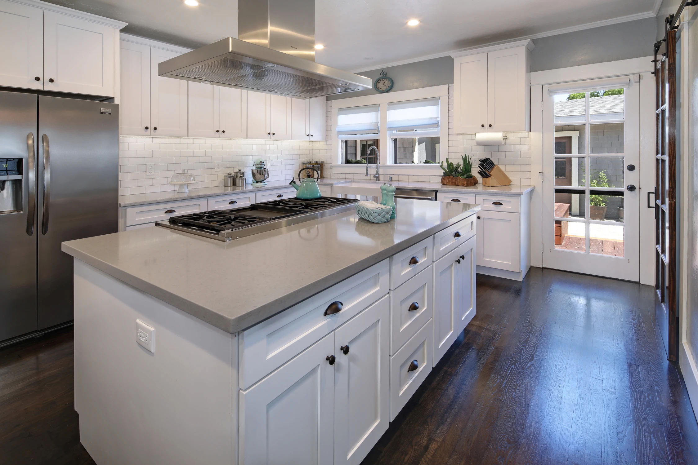 White kitchen with central island, stainless refrigerator, and garden doors