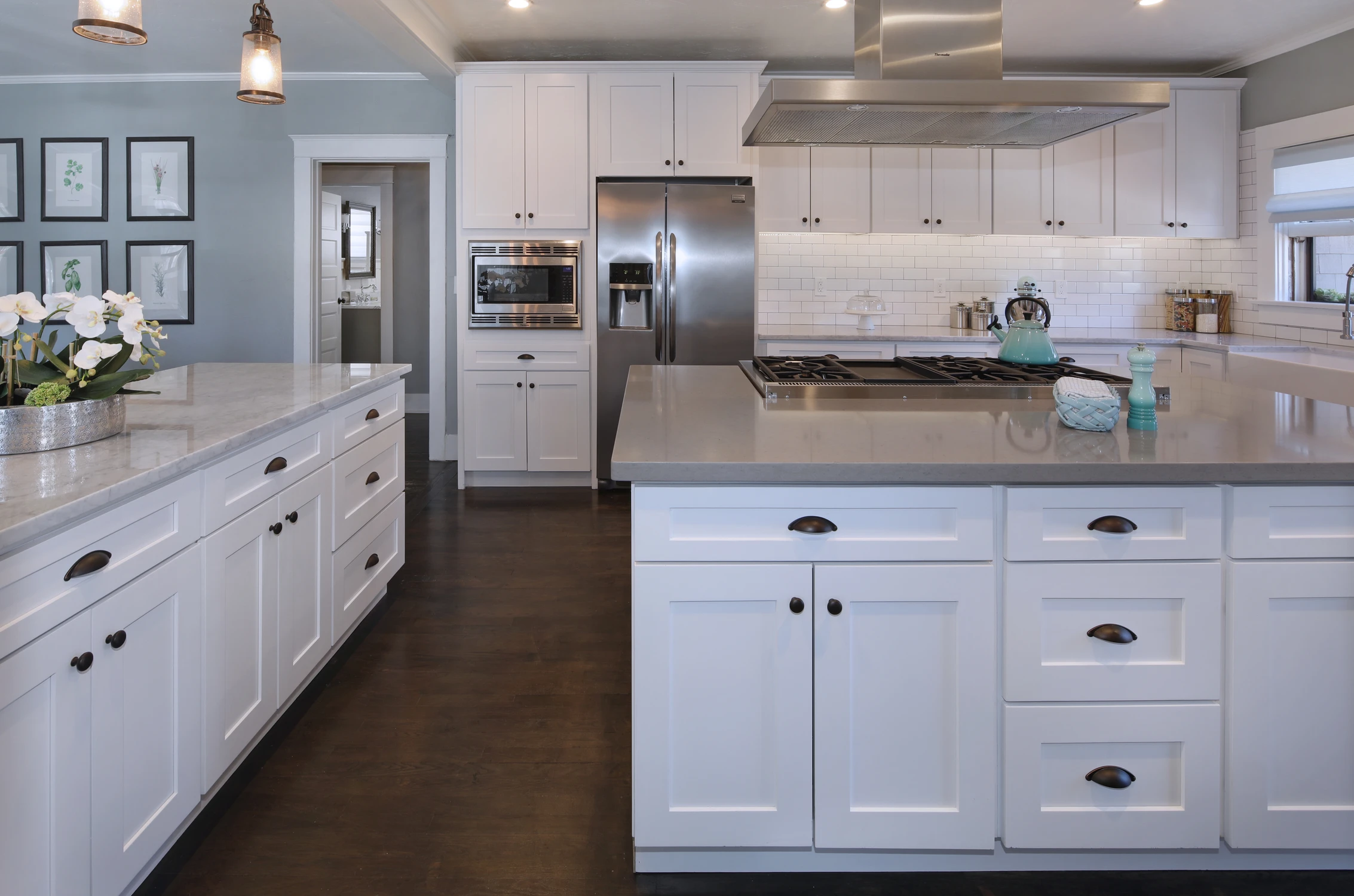 Long white kitchen counter with built-in refrigerator and layered pendants