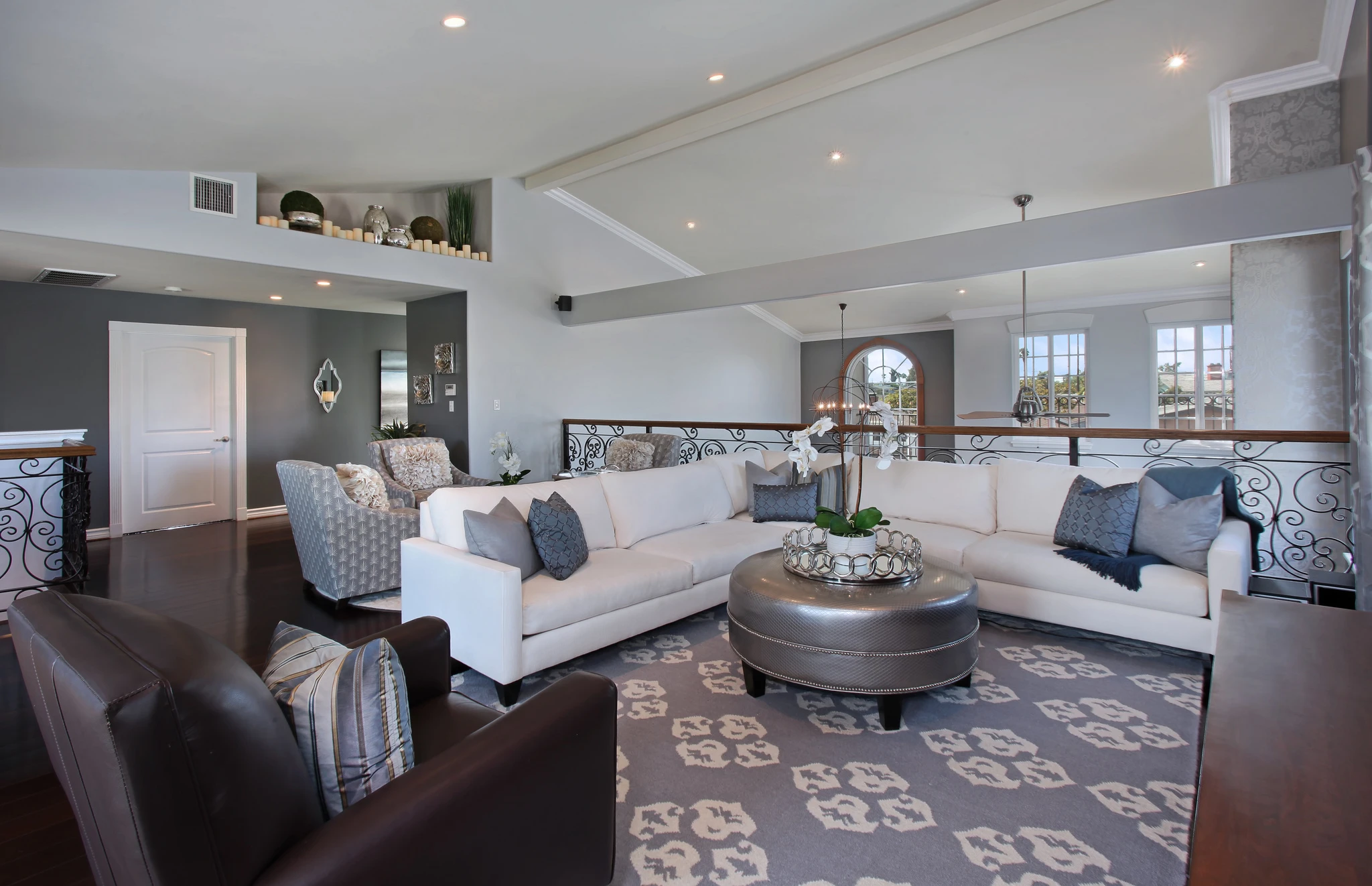 Loft sitting area with white sectional, dark rug, and open railing