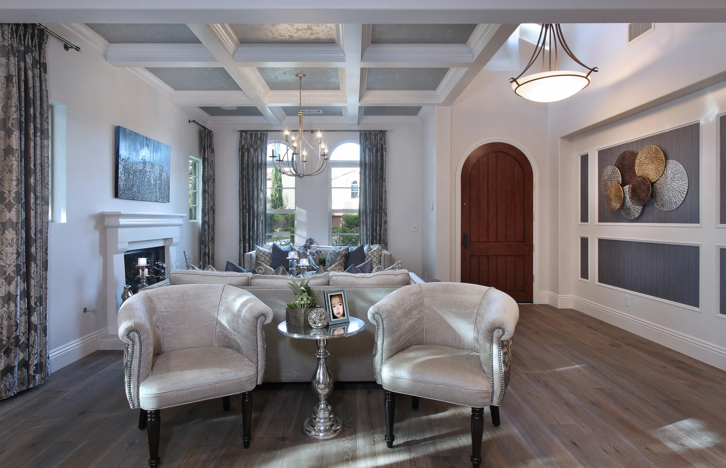 Living room with white armchairs, dark wood floor, and large arched door