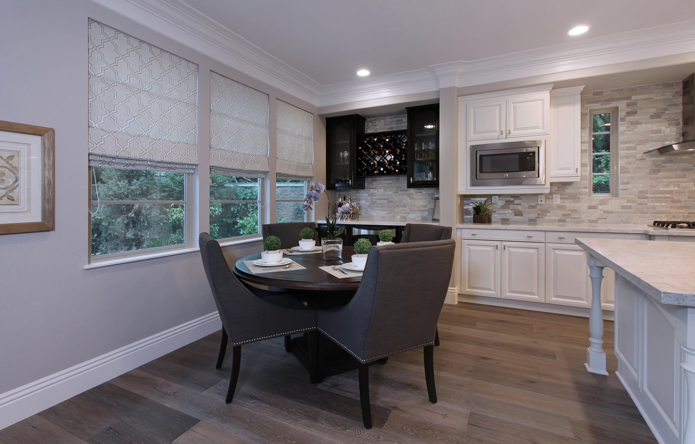 Kitchen dining nook beside white cabinetry and dark patterned backsplash