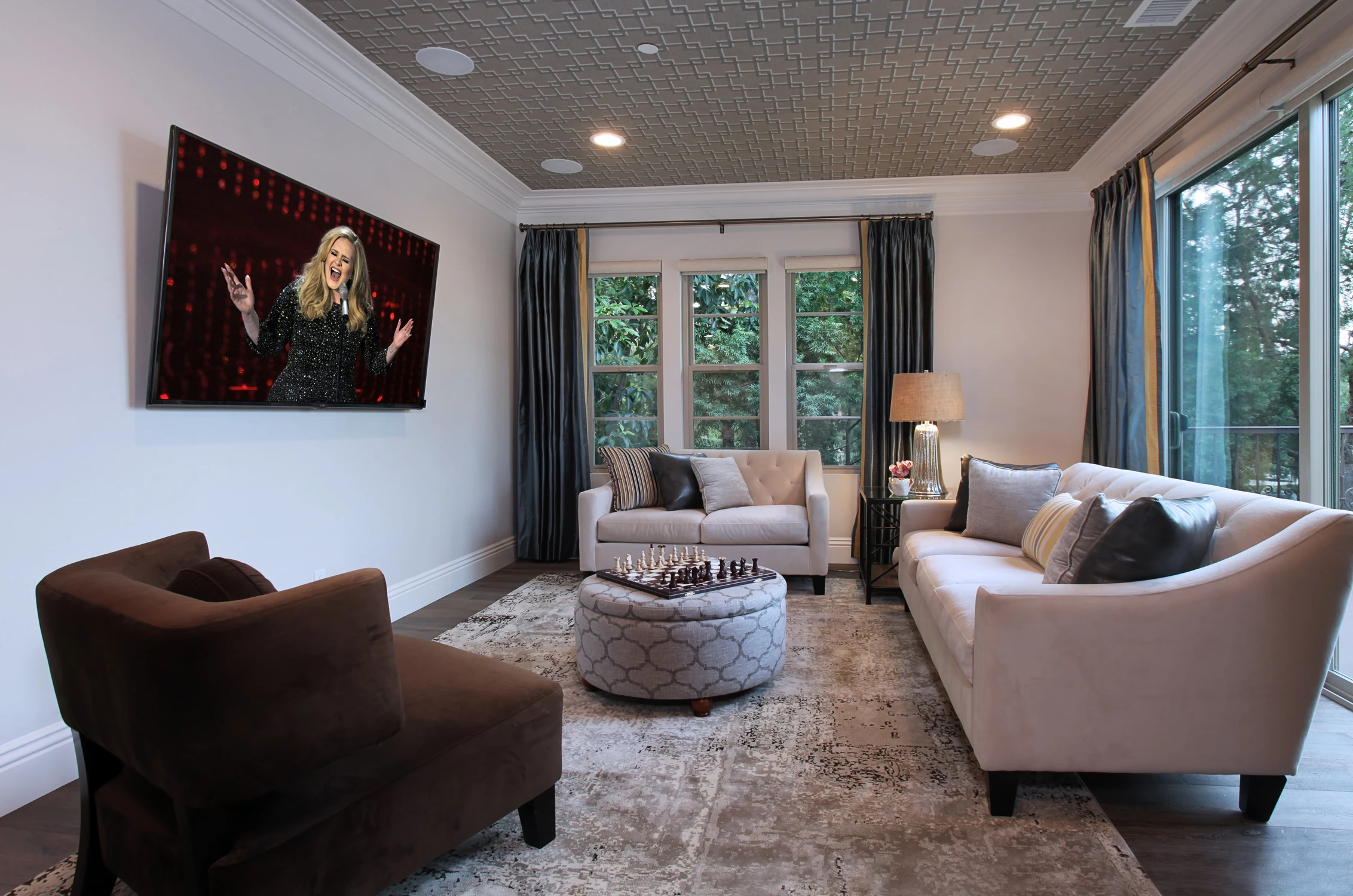 Bonus room with brown lounge chairs, pale rug, and large framed art