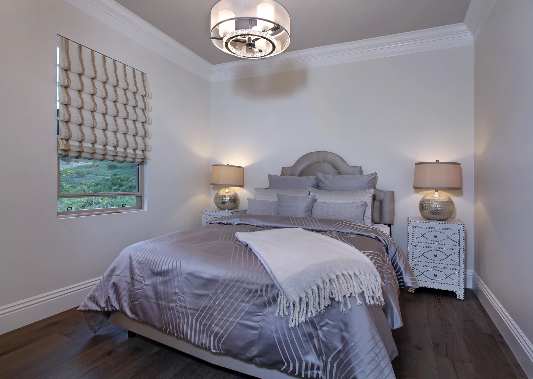 Bedroom with gray bed, patterned Roman shade, and white nightstands