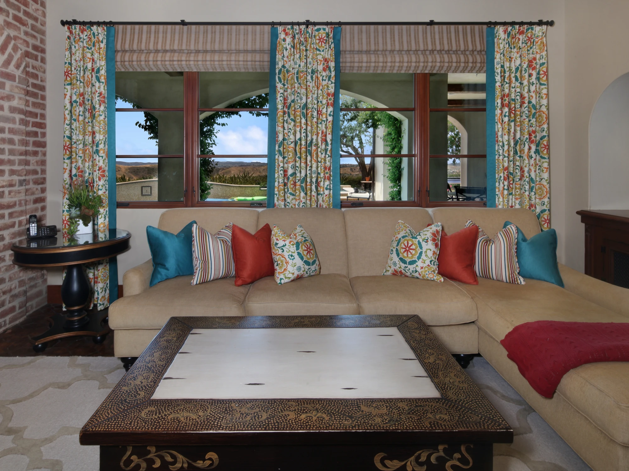 Family room window seat with patterned curtains and bright accent pillows