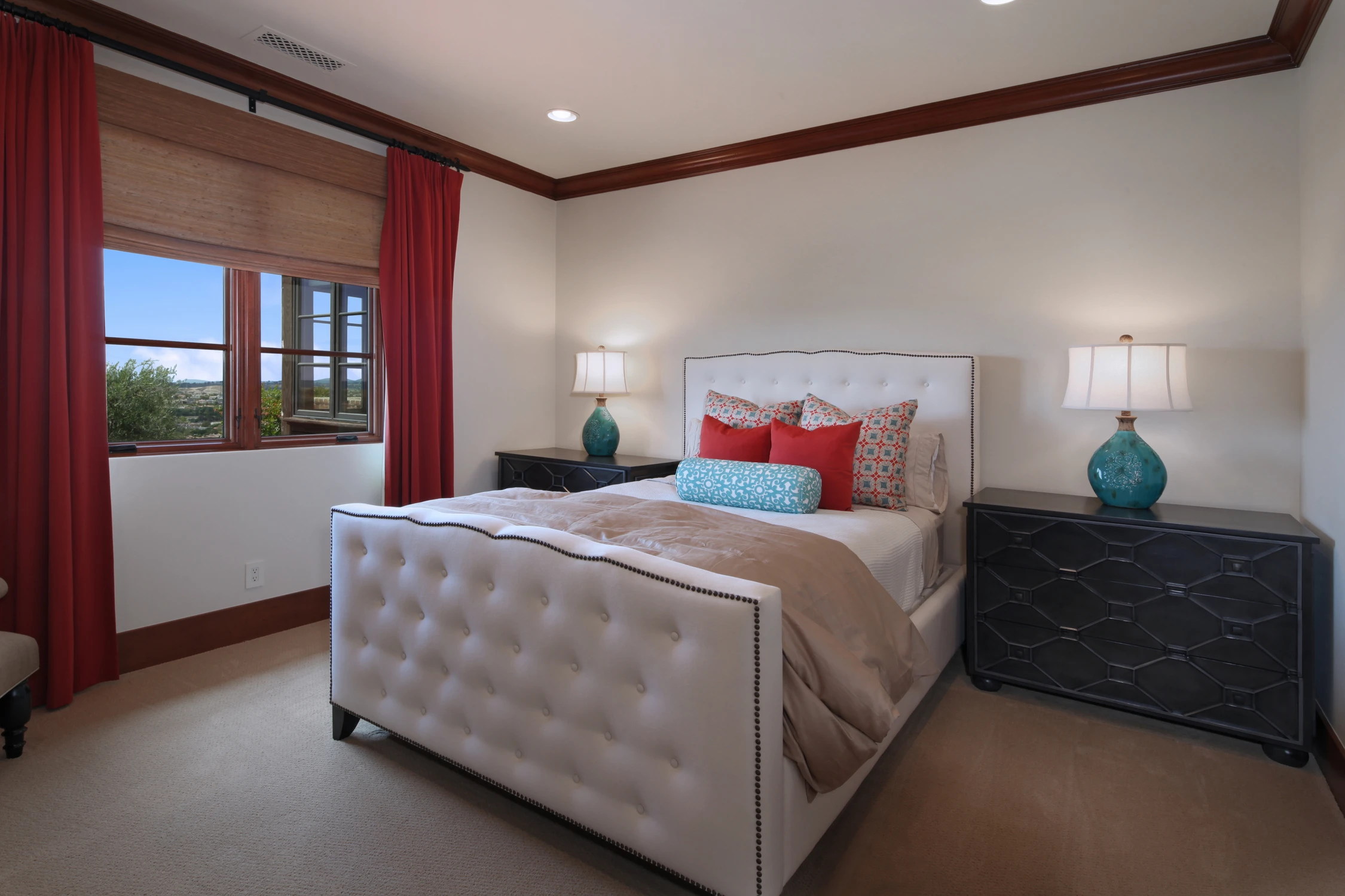 Bedroom with white tufted bed, red drapery, and dark nightstands