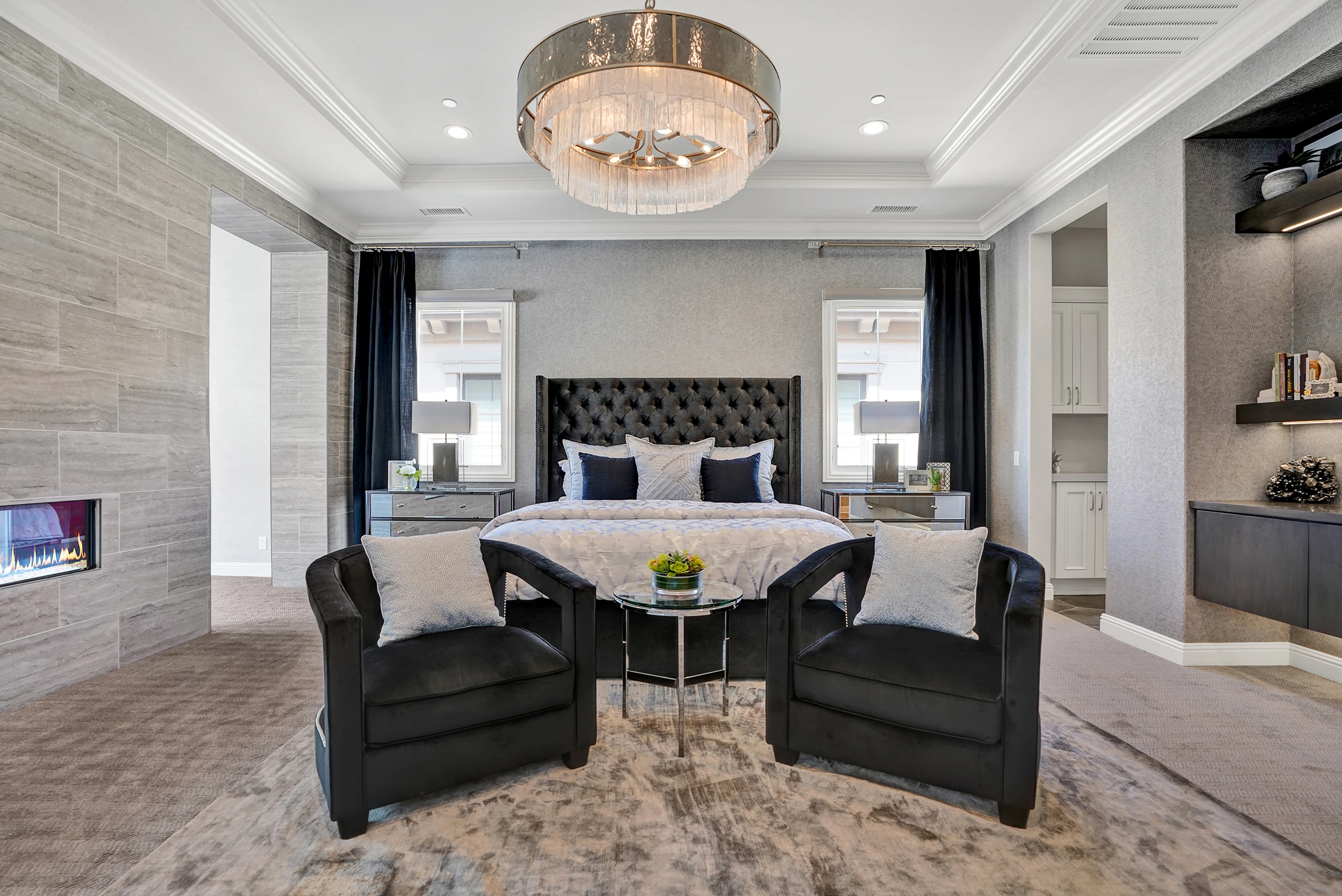 Black tufted bed and matching lounge chairs in a dramatic gray bedroom