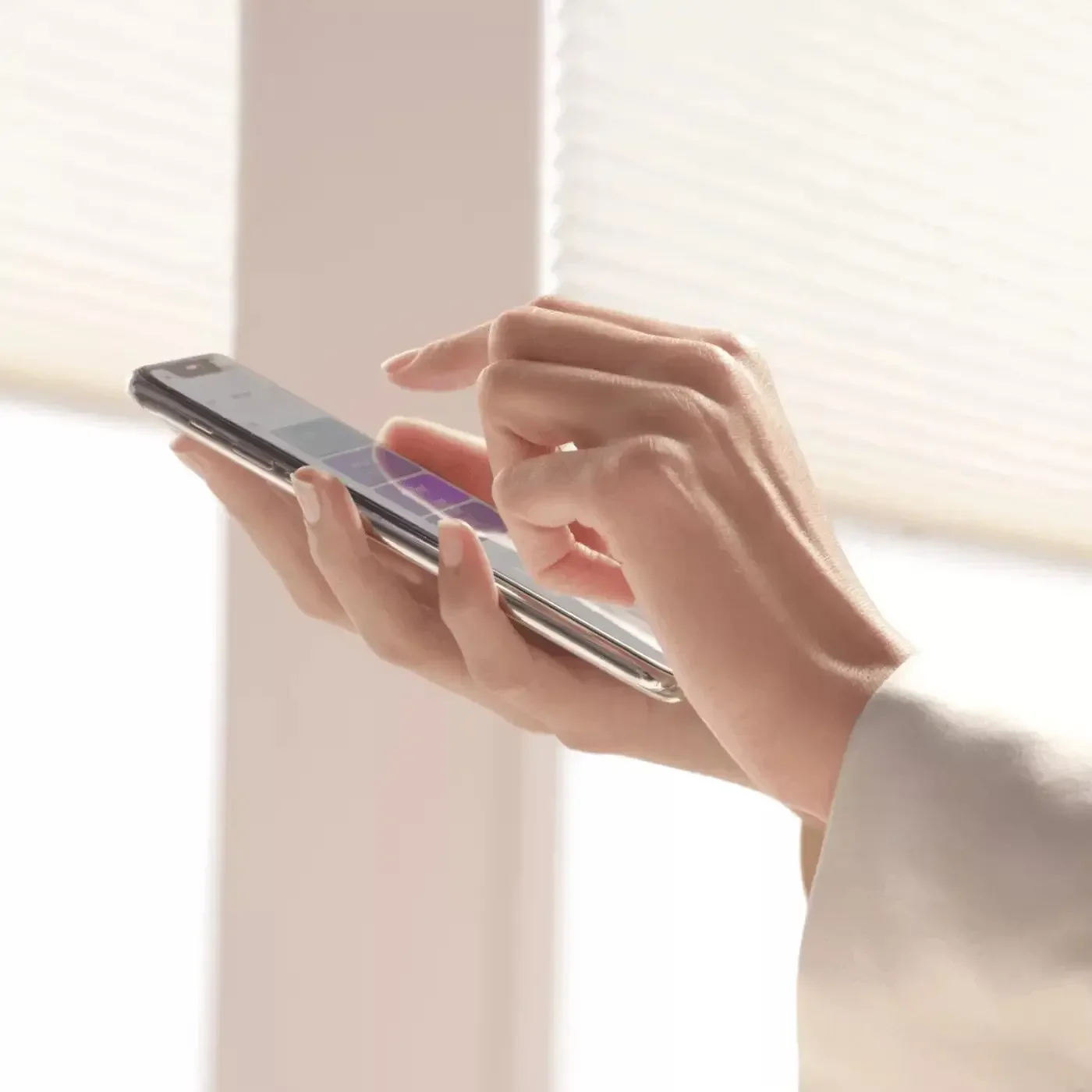 Person using a smartphone to control motorized window treatments