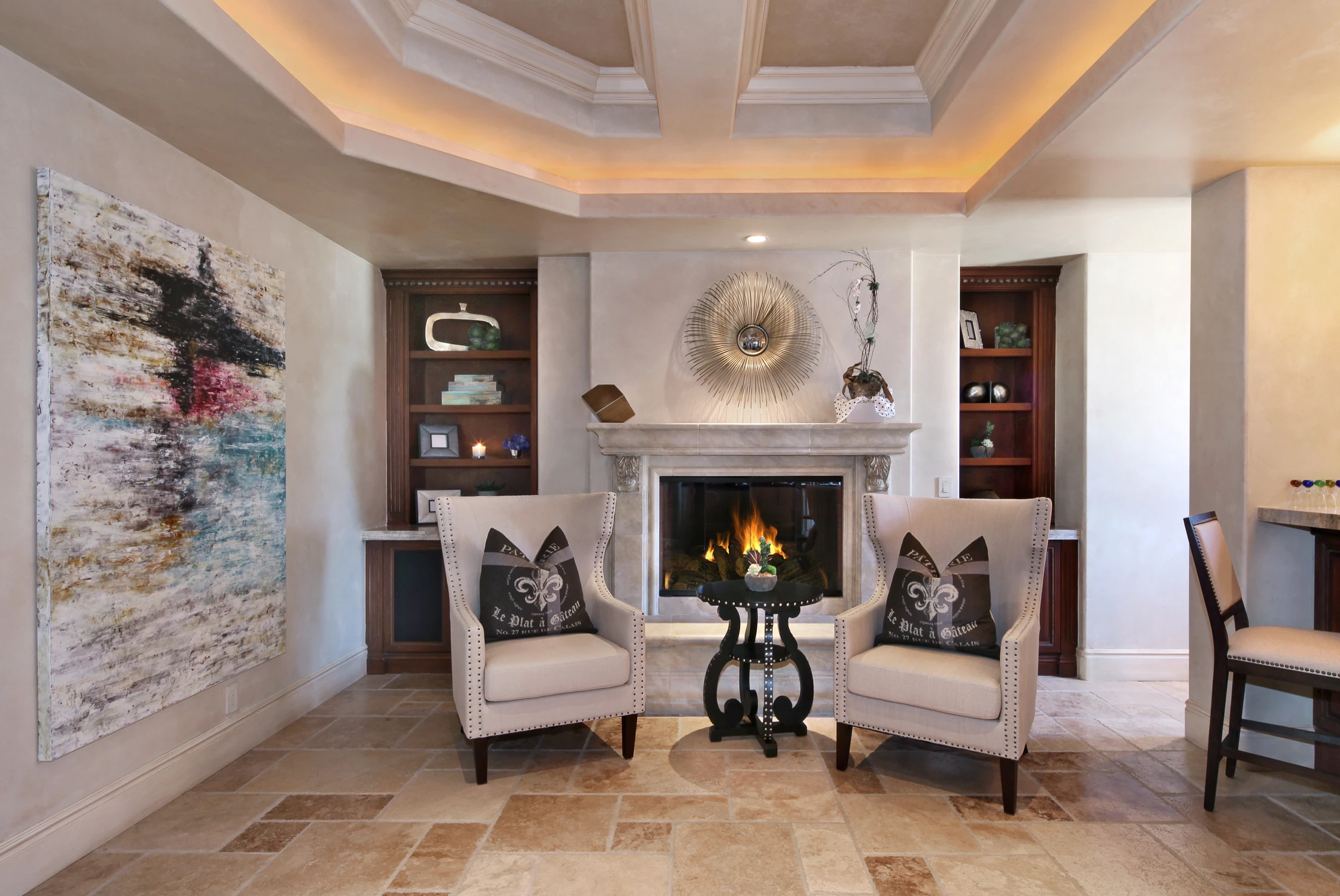Living room fireplace wall with wingback chairs and warm uplighting