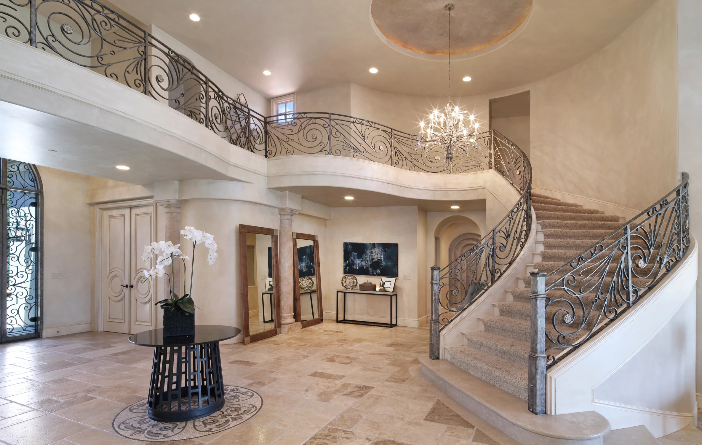 Grand entryway with curved staircase, stone flooring, and wrought iron railing