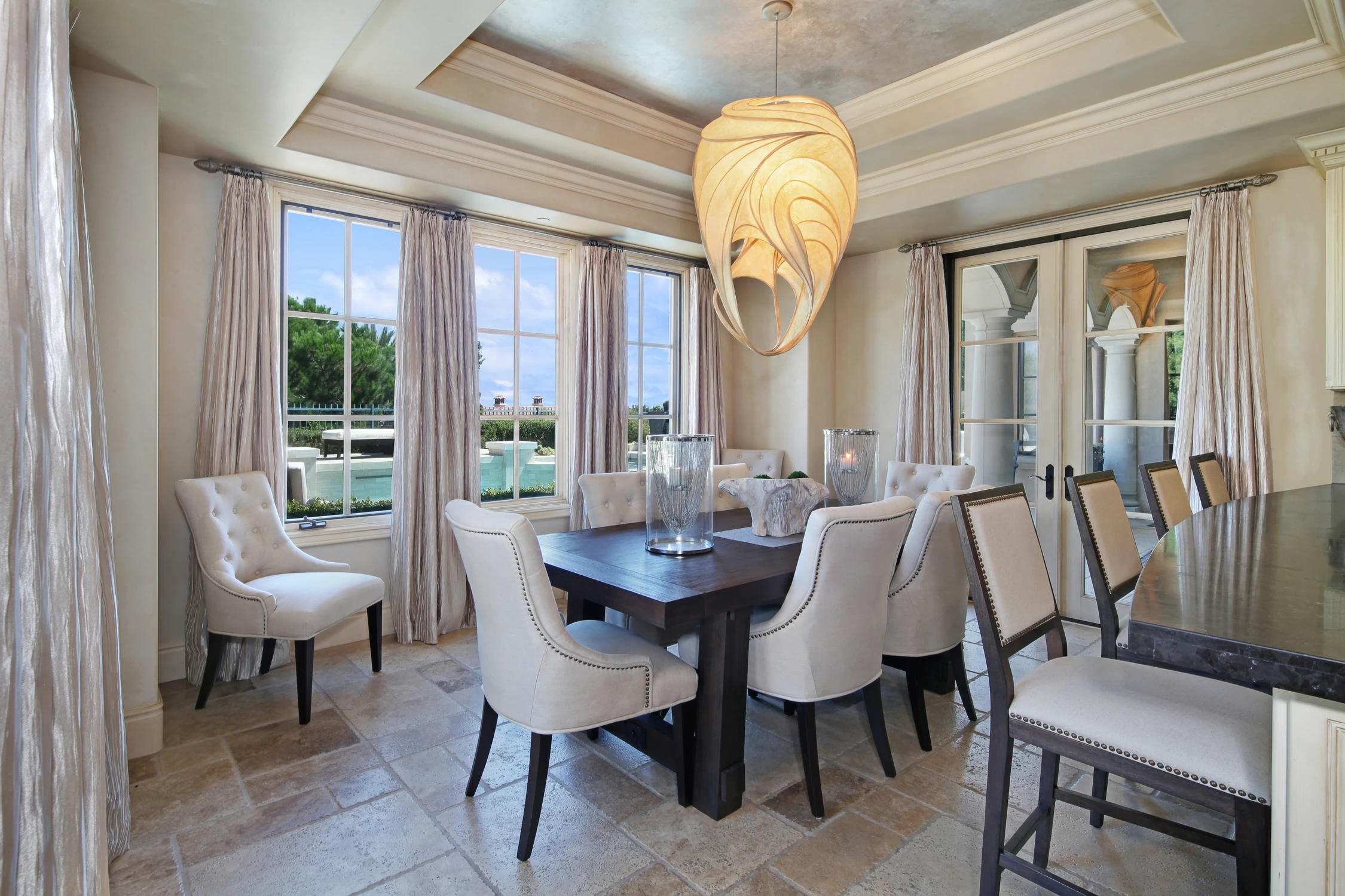 Dining nook with tall windows, curved curtains, and round pendant light