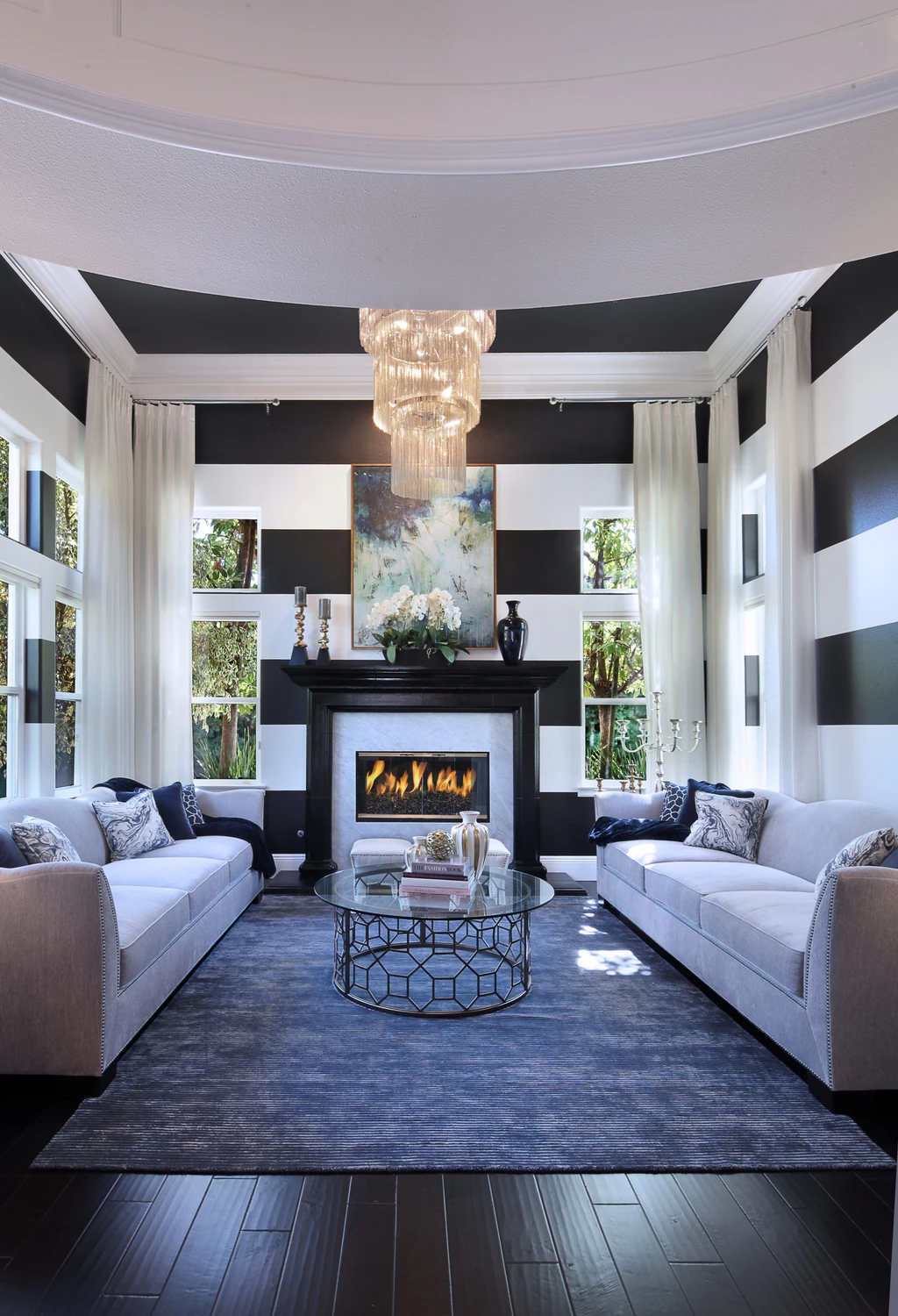 Living room with blue rug, fireplace, and dark drapery