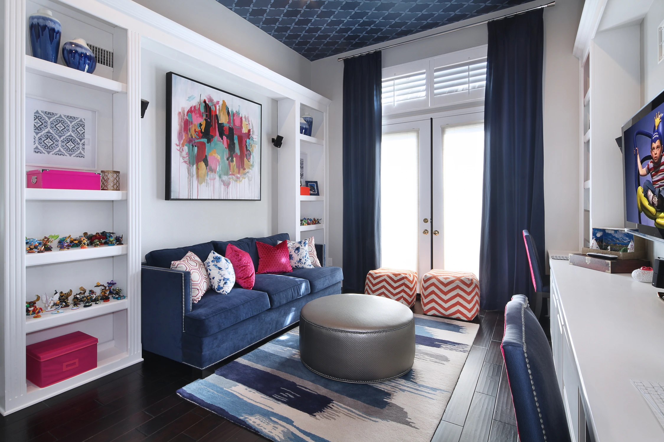 Playroom with navy sofas, bright shelving, and patterned rug