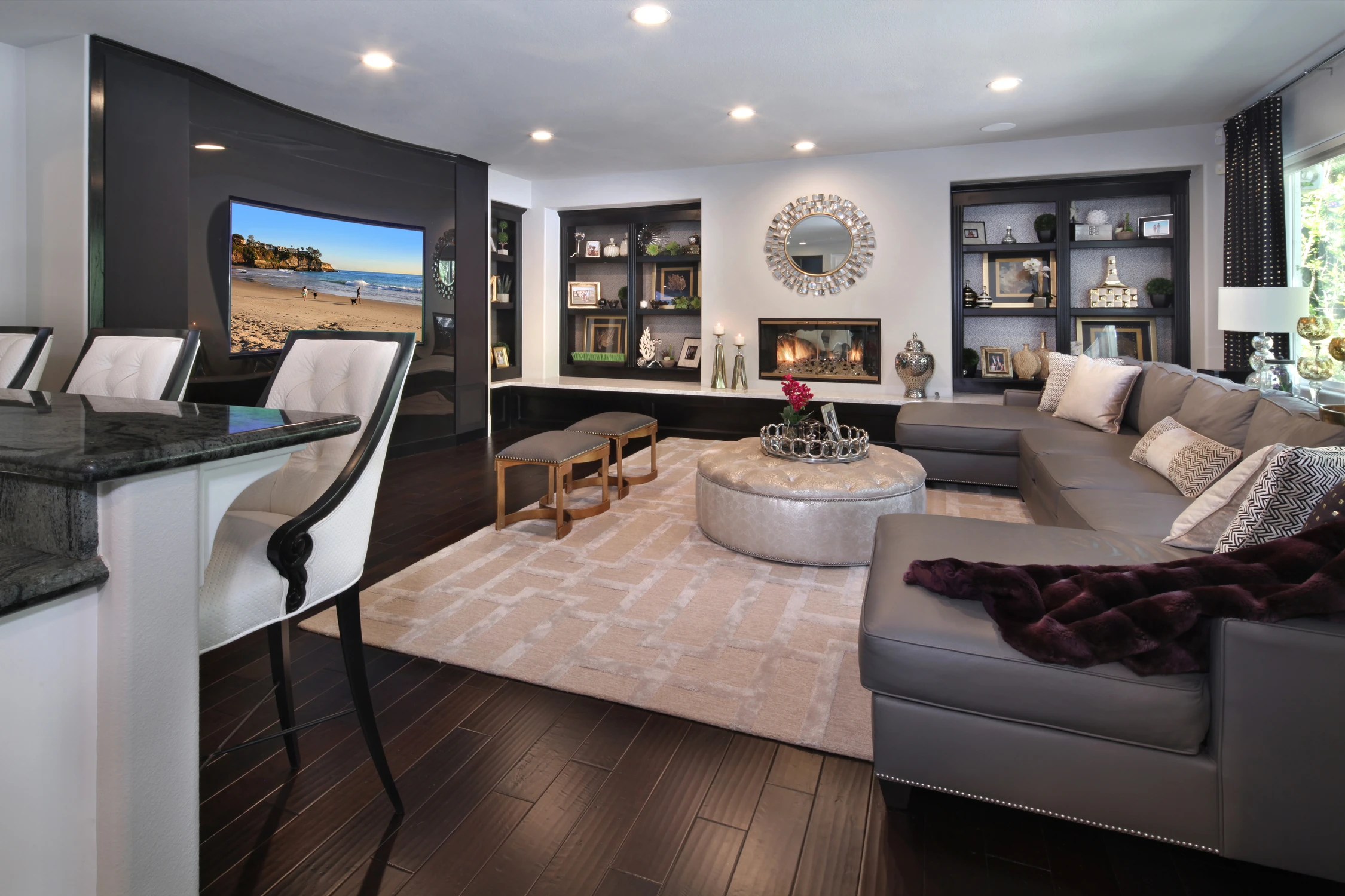 Family room with black built-ins, fireplace, and round ottoman