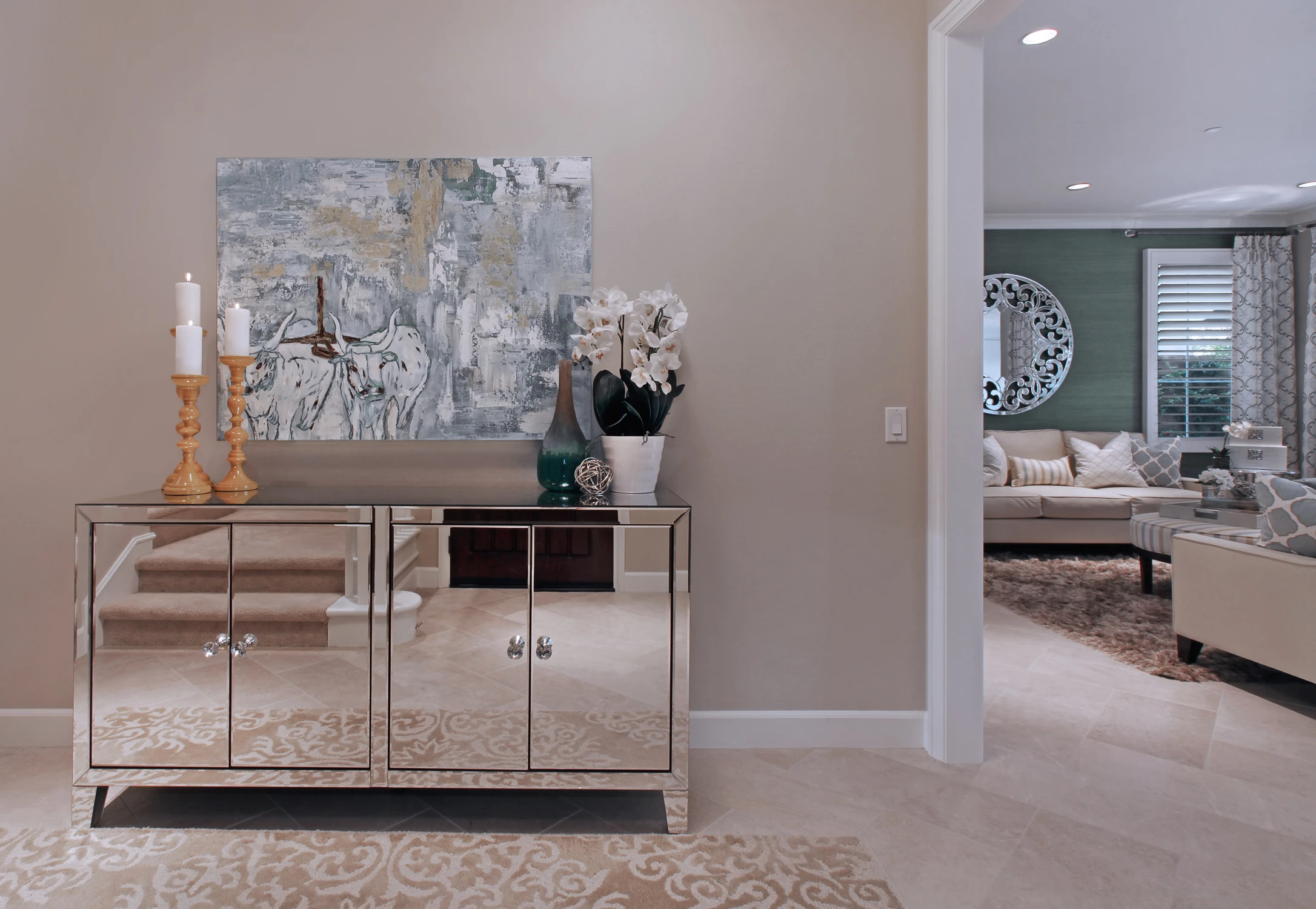 Entryway with mirrored console, staircase, and view into living room