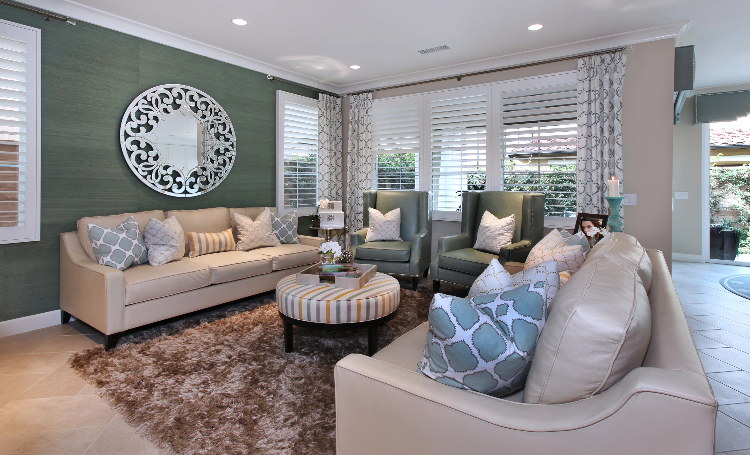 Living room with green accent wall, white sofas, and round ottoman