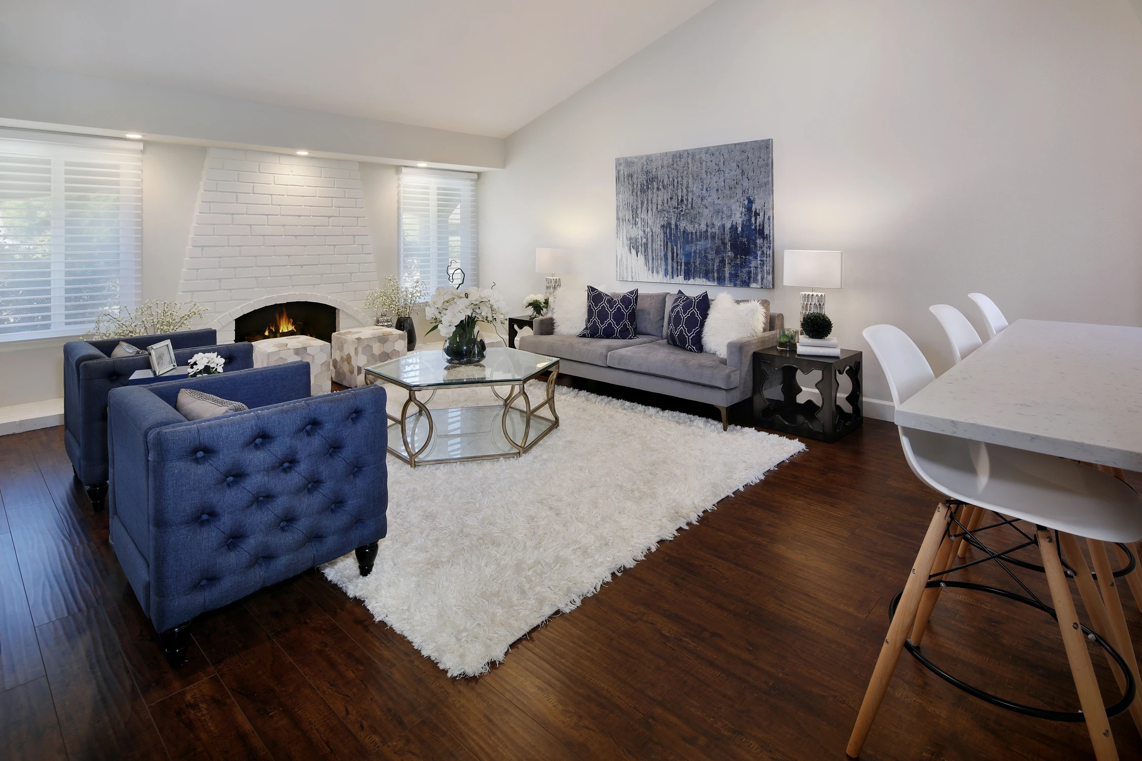 Open lounge with navy armchair, pale sofa, and white shag rug