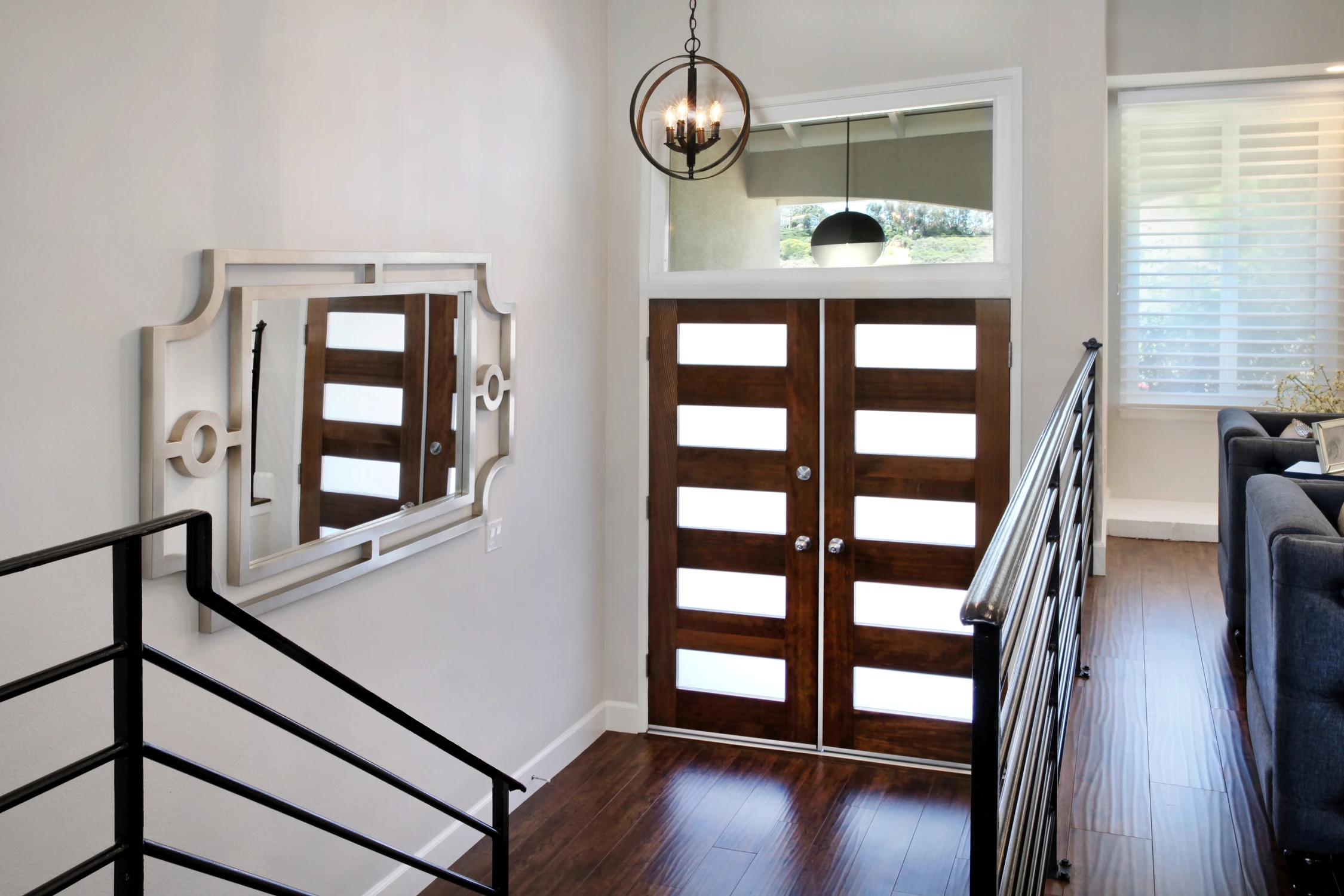 Upper entry landing with wood doors, lantern pendant, and dark railing