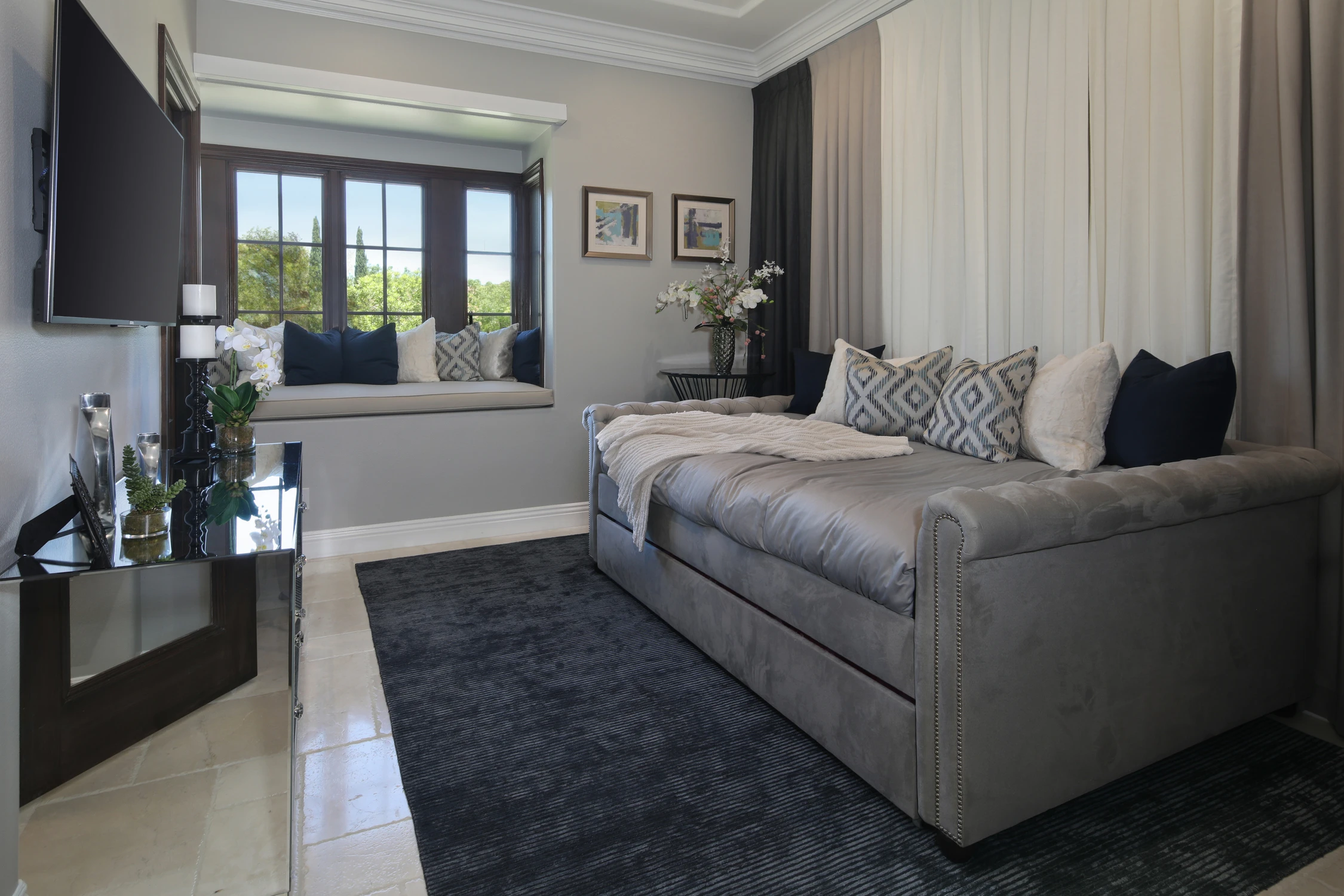 Guest room with custom queen-size trundle-style daybed, dark rug, and black-framed glass doors