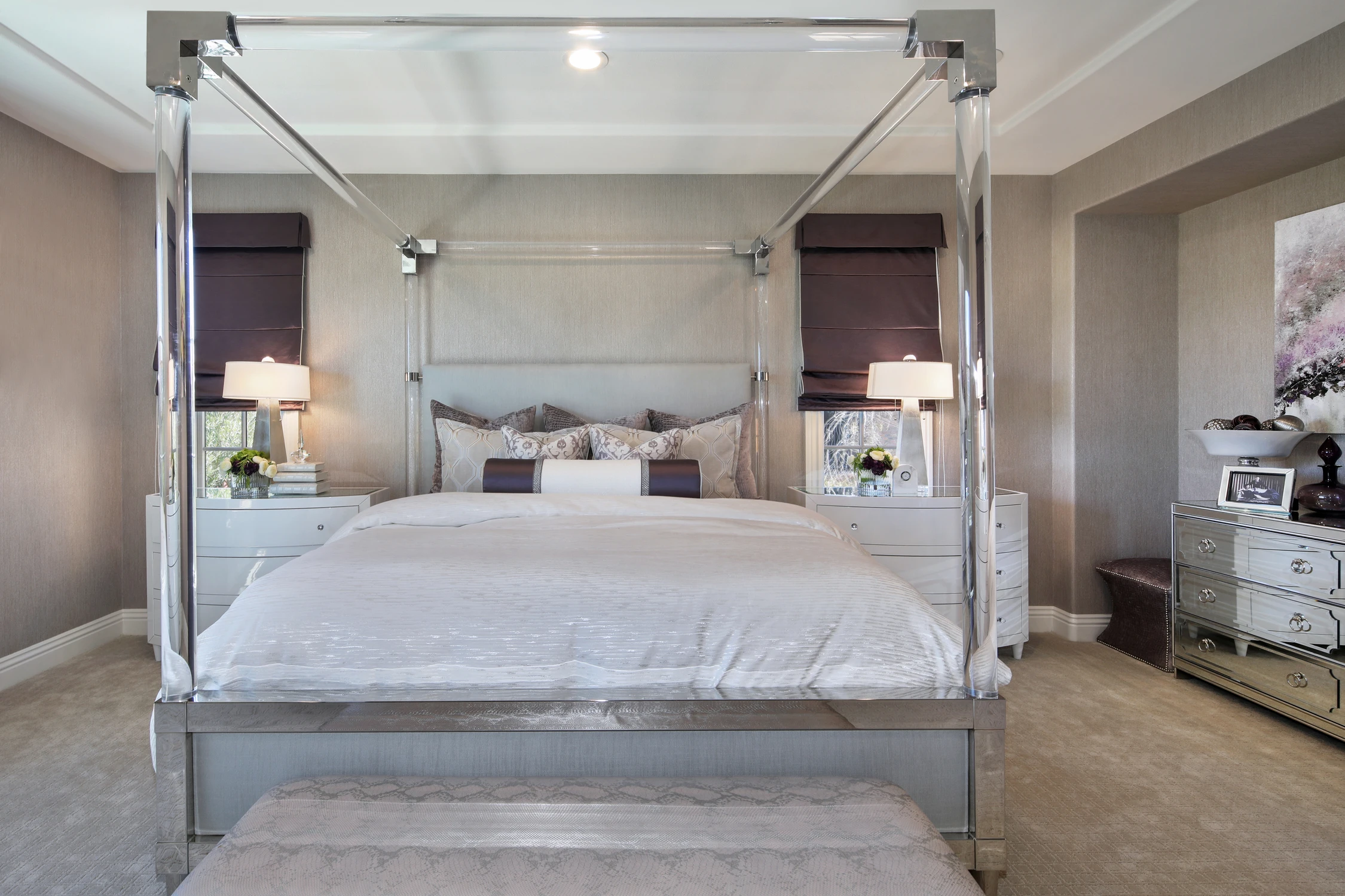 Primary bedroom with acrylic poster bed, white nightstands, and textured wallpaper