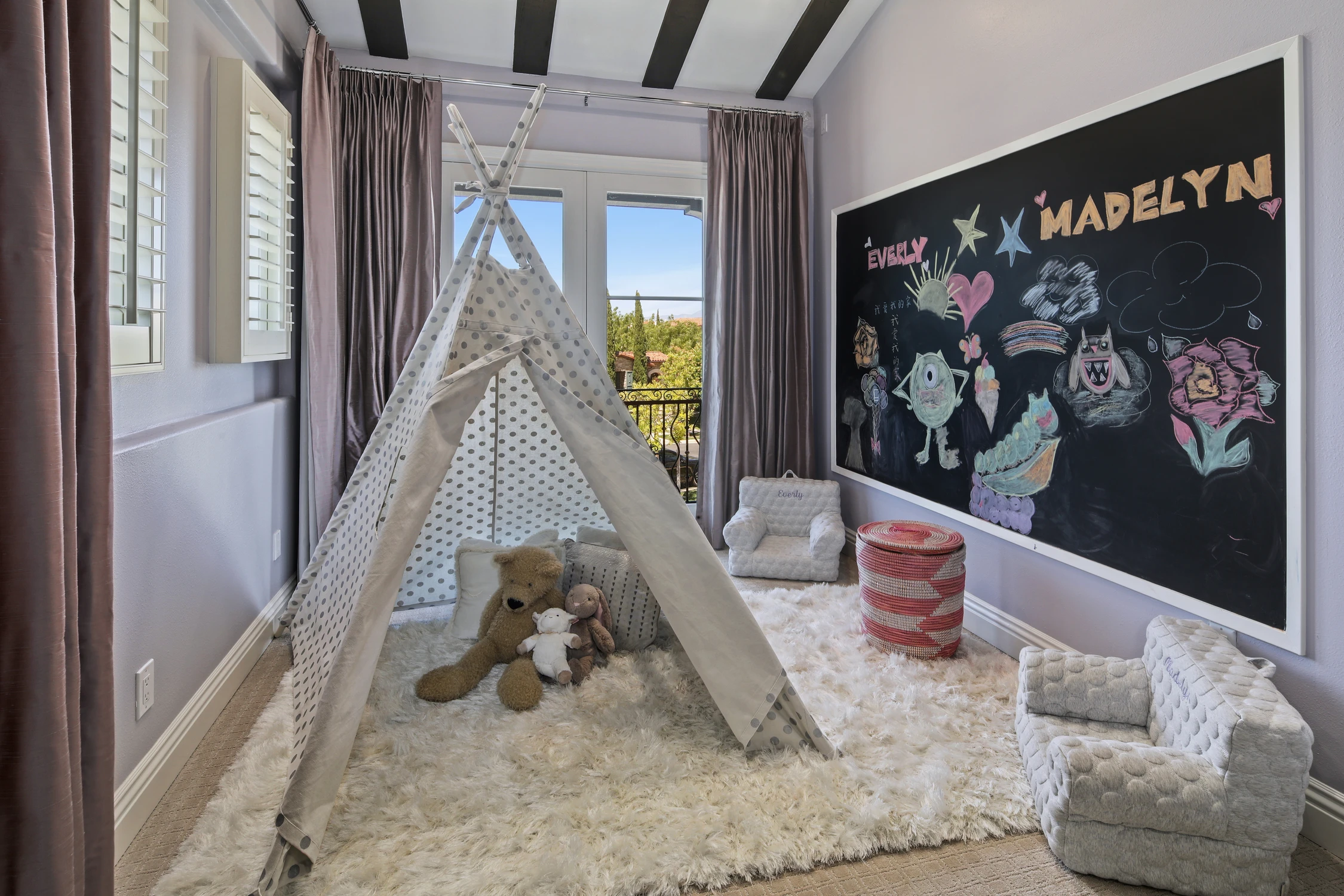 Children's playroom with indoor tent, shag rug, playful wall art, and stuffed animals