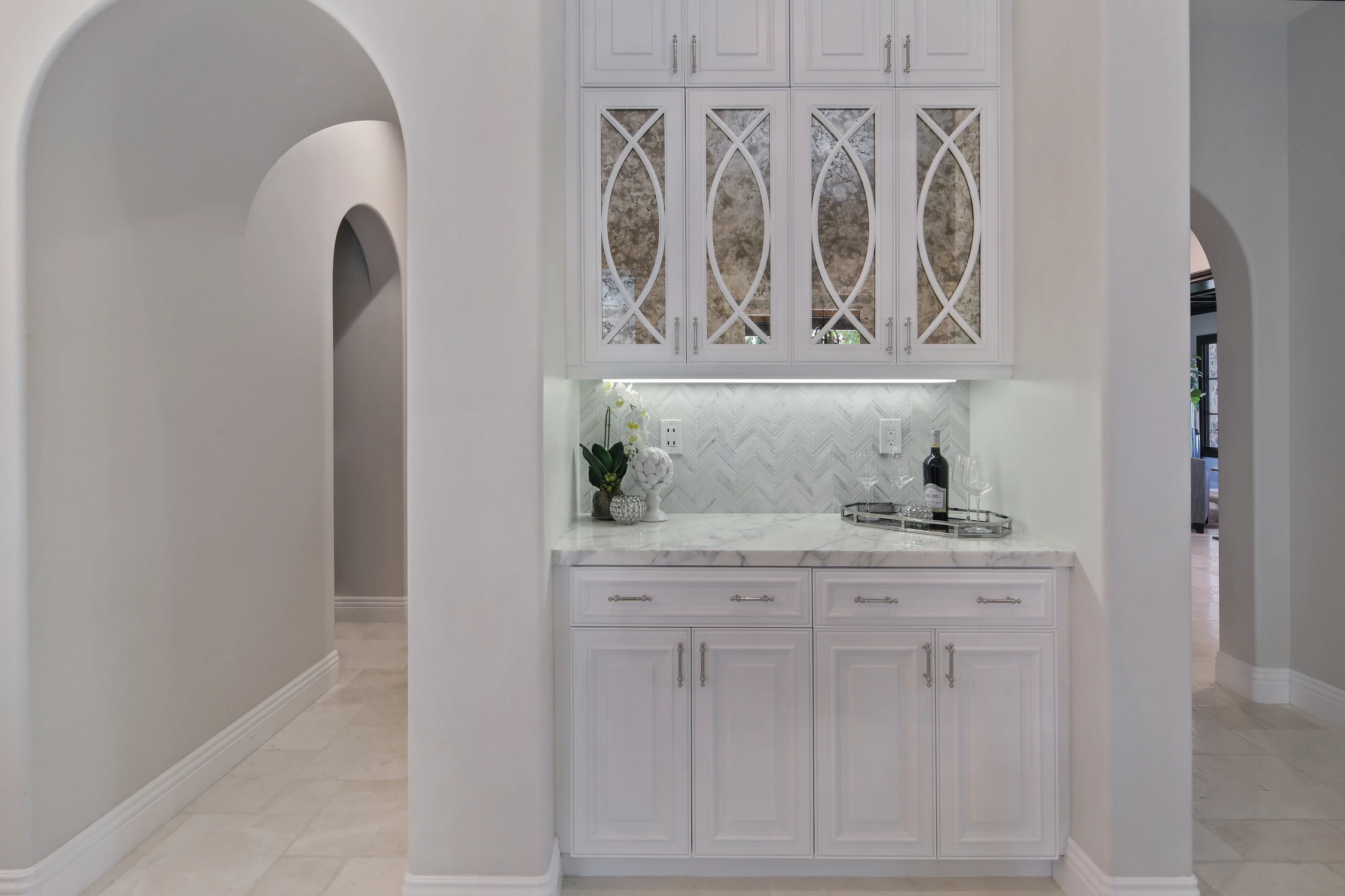 White kitchen cabinet wall with glass doors and pale tile backsplash