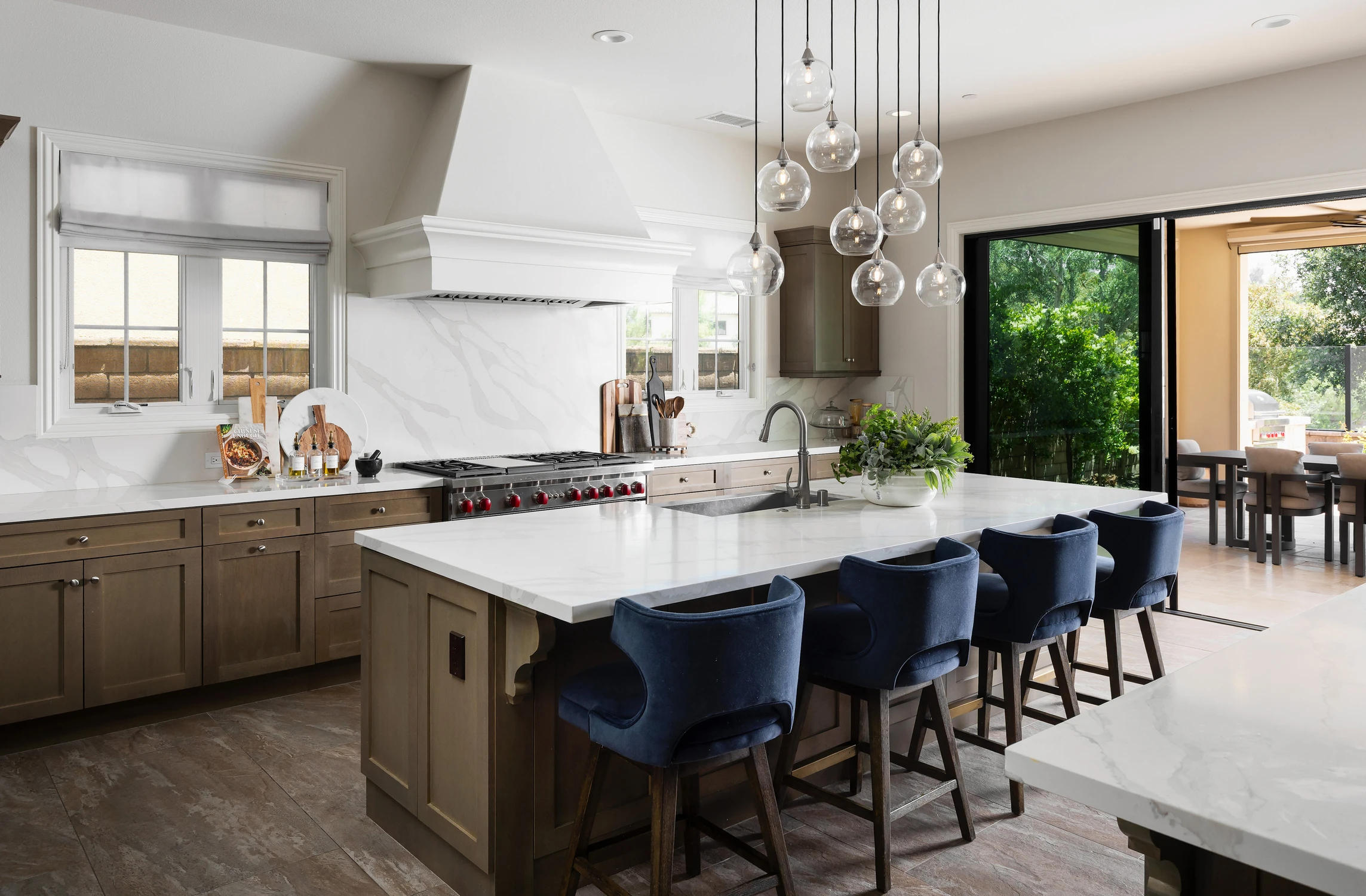 Kitchen with large island, range hood, and blue bar stools