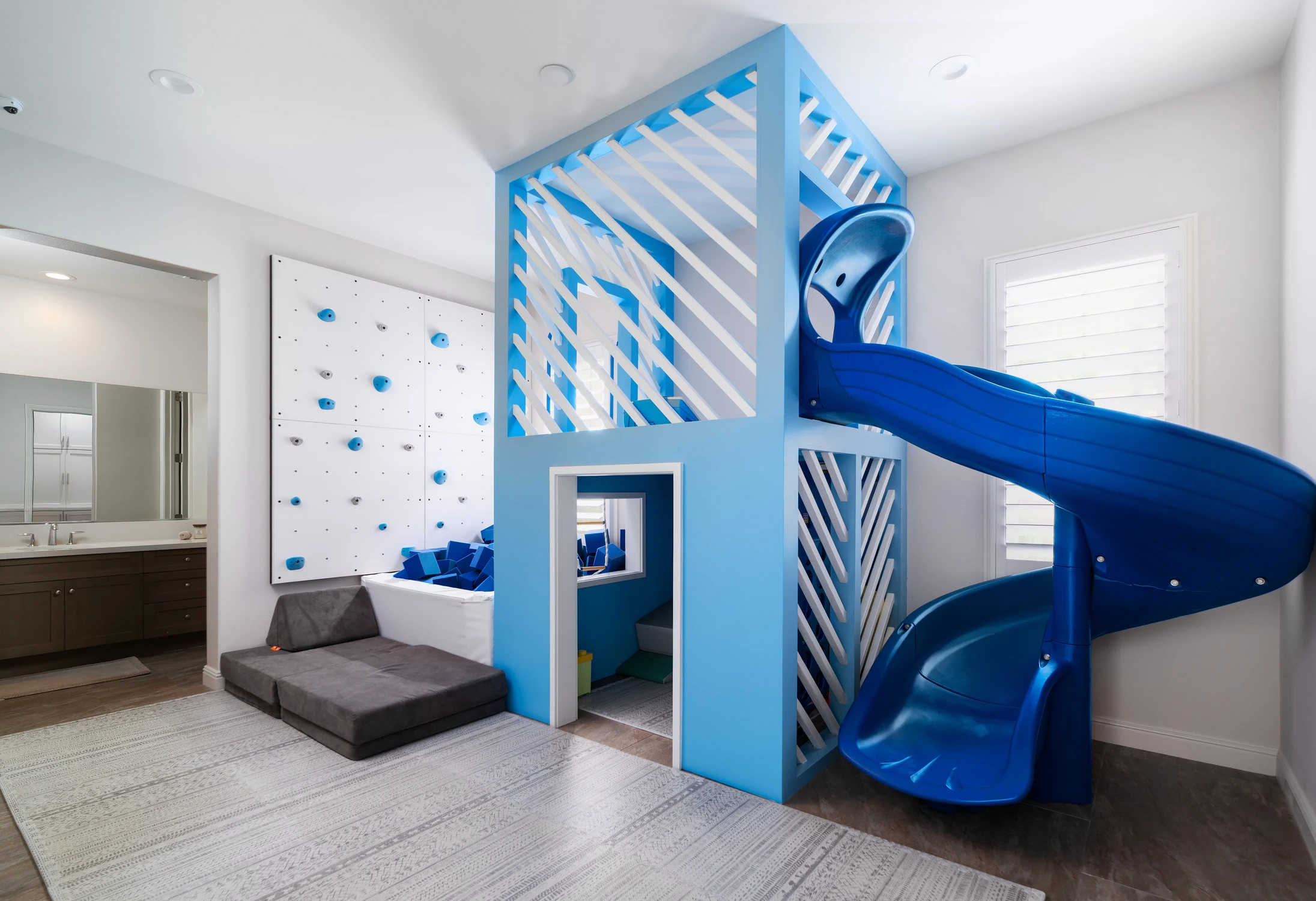 Kids playroom with blue slide, climbing wall, and indoor structure
