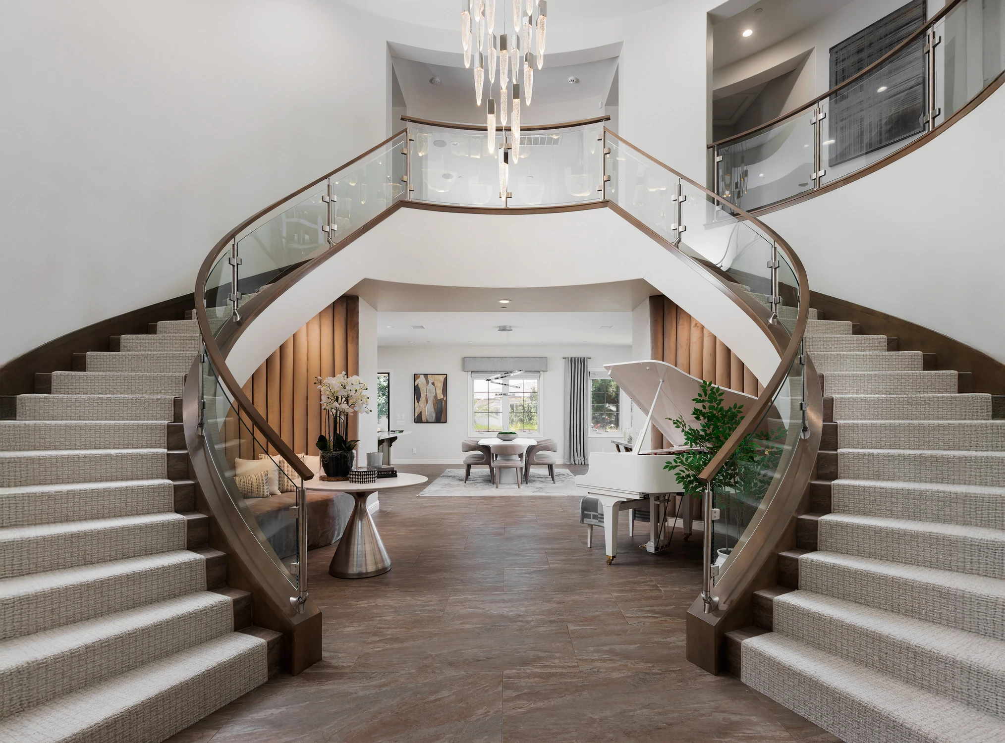 Curved staircases framing a piano and dining area