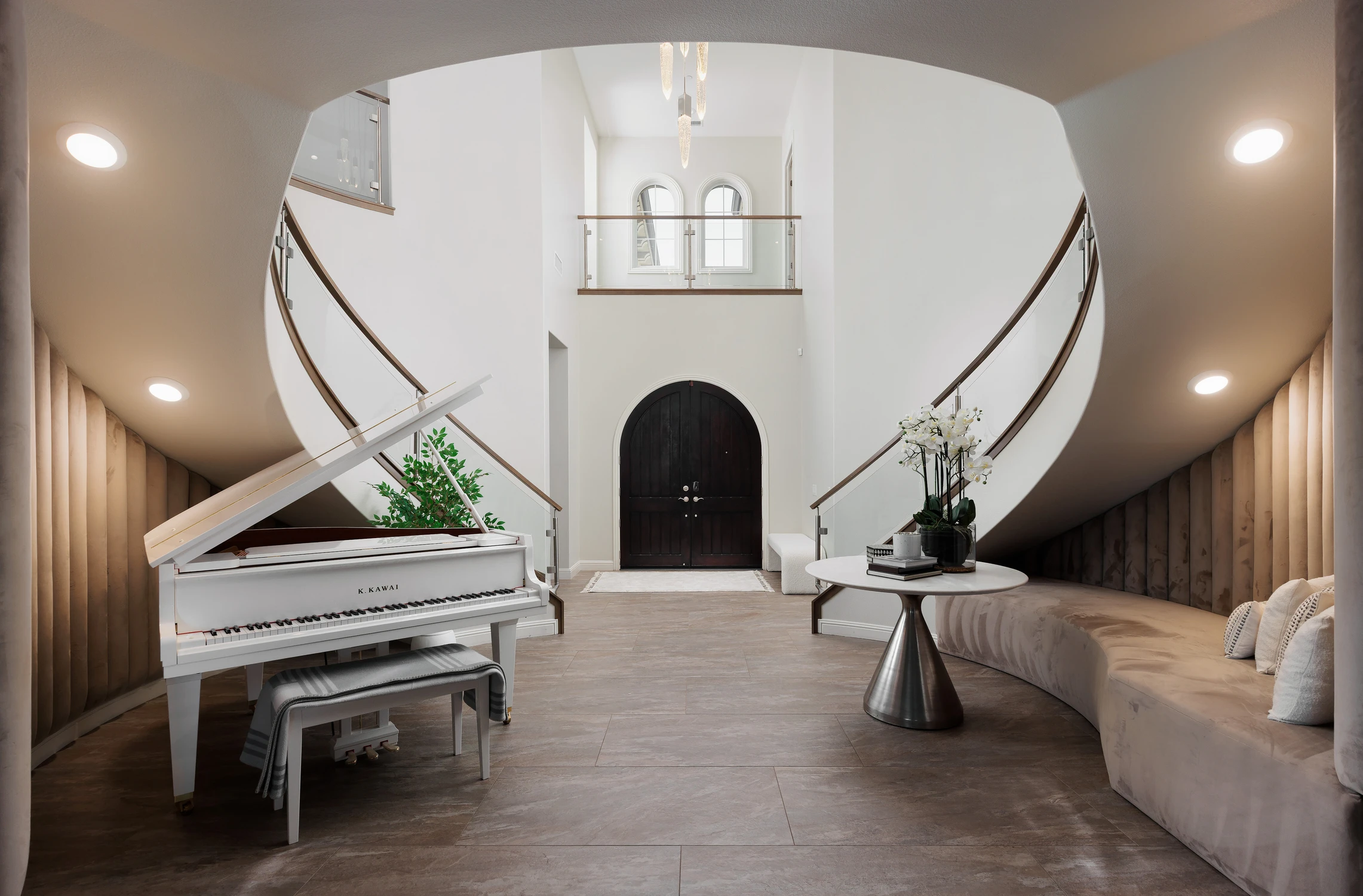 Entry with arched double doors, piano, and curved staircases