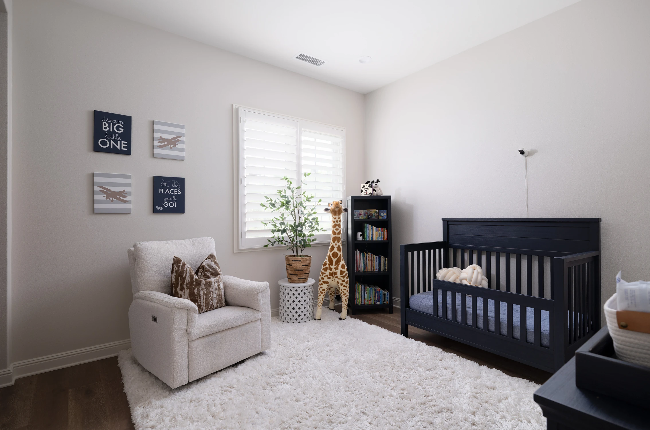 Nursery with dark crib, reading chair, and plush rug