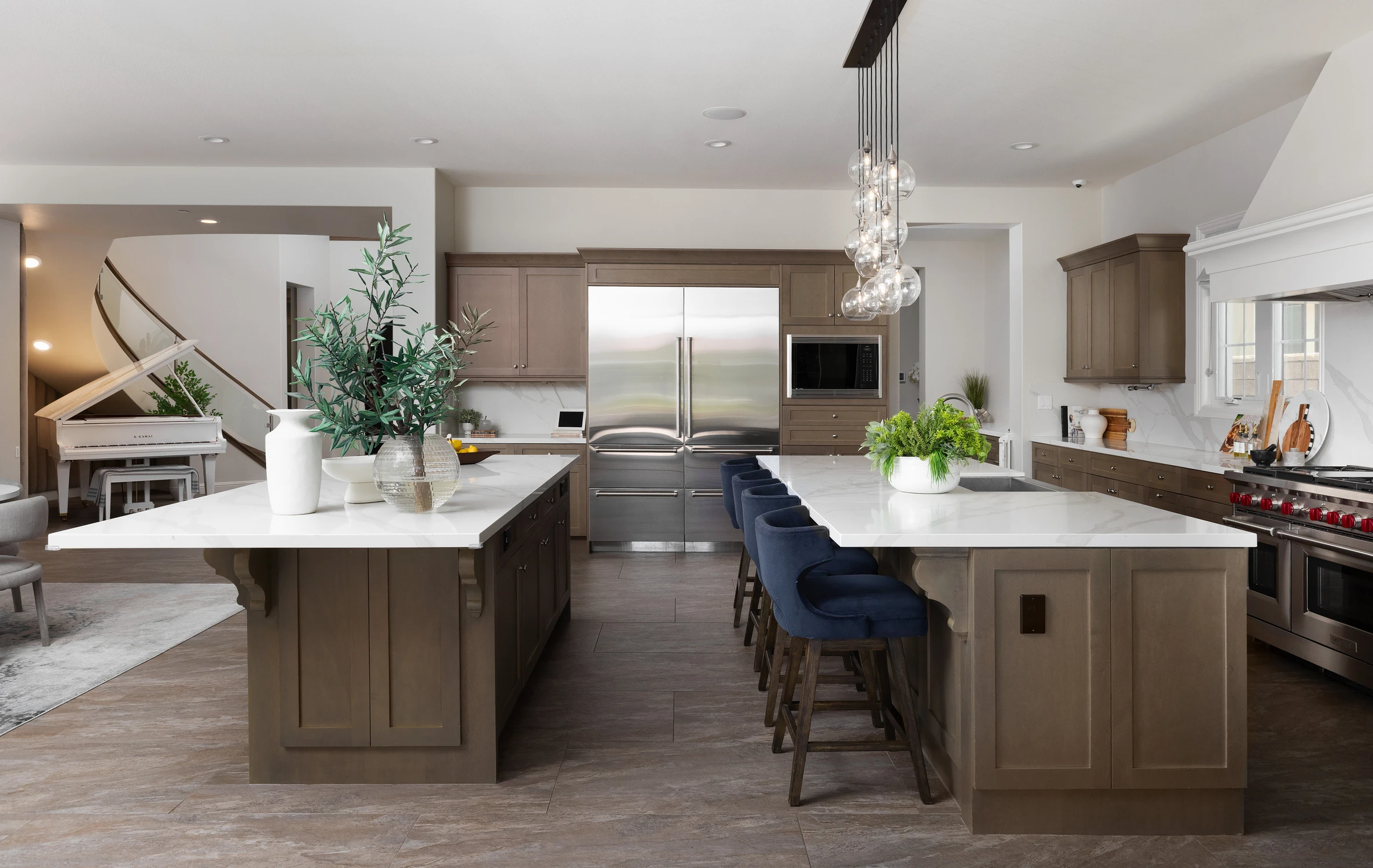 Kitchen with two islands, dark cabinetry, and blue stools