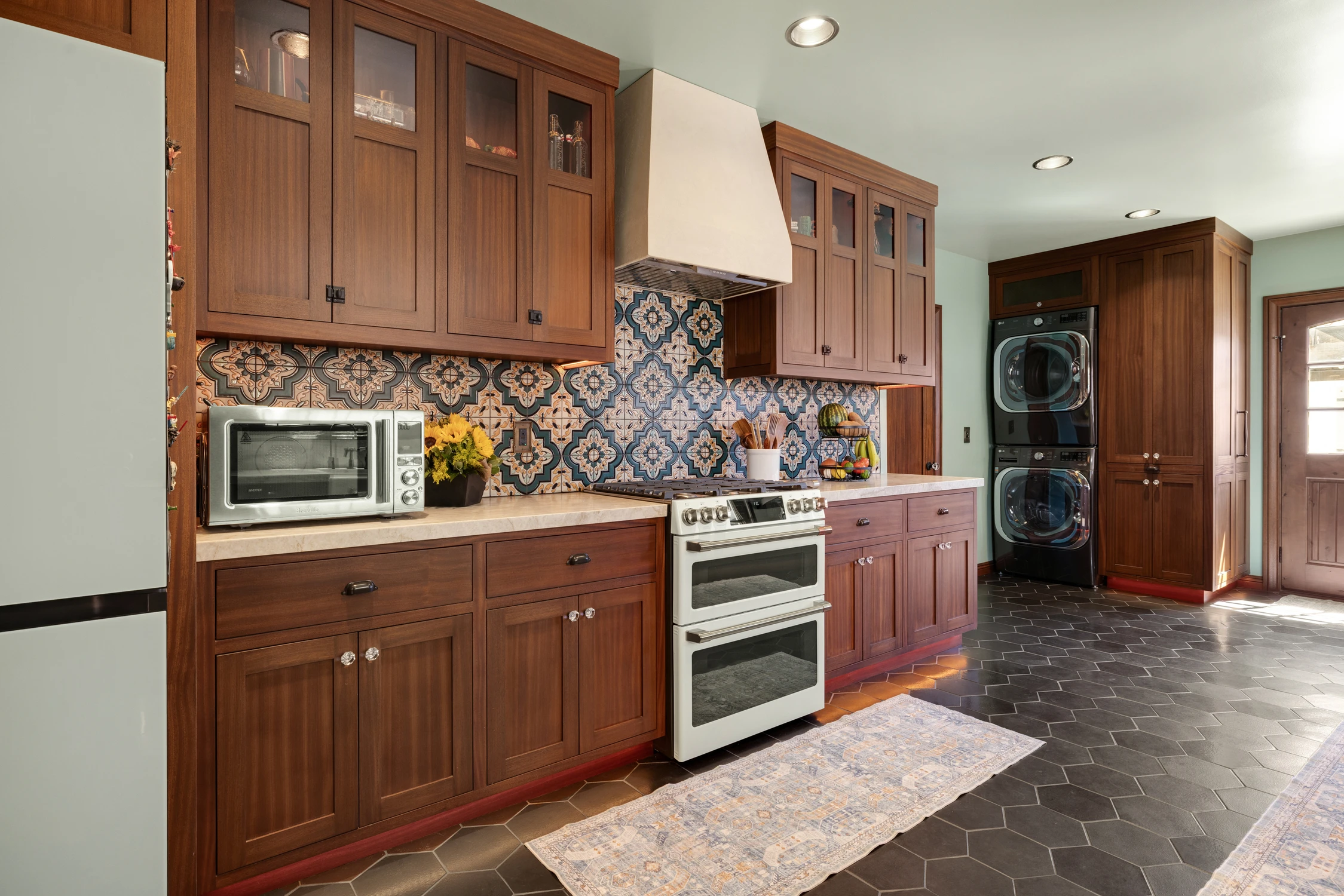 Warm wood kitchen with patterned tile backsplash and dark stone floor