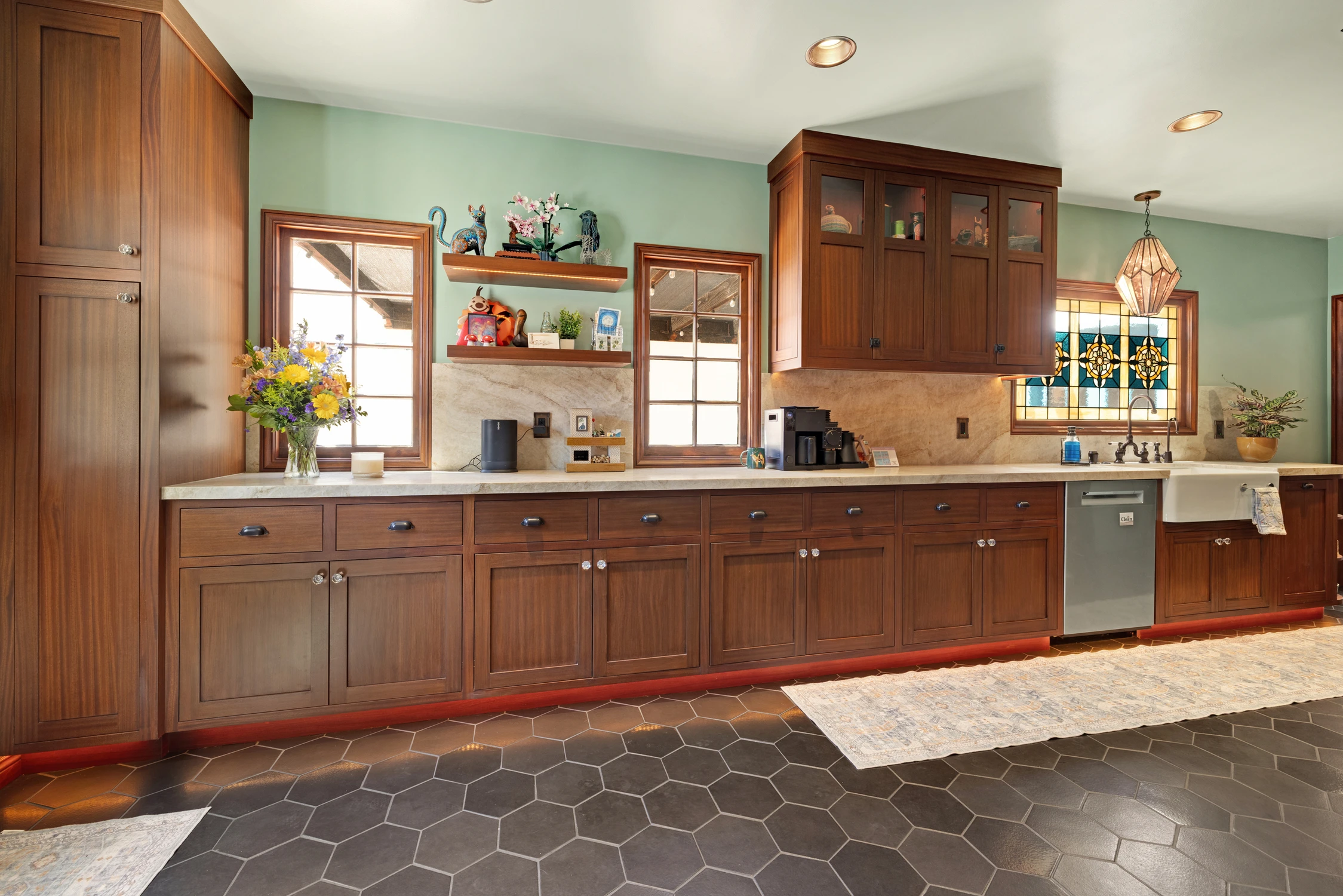 Long wood kitchen counter beneath green wall and stained-glass window