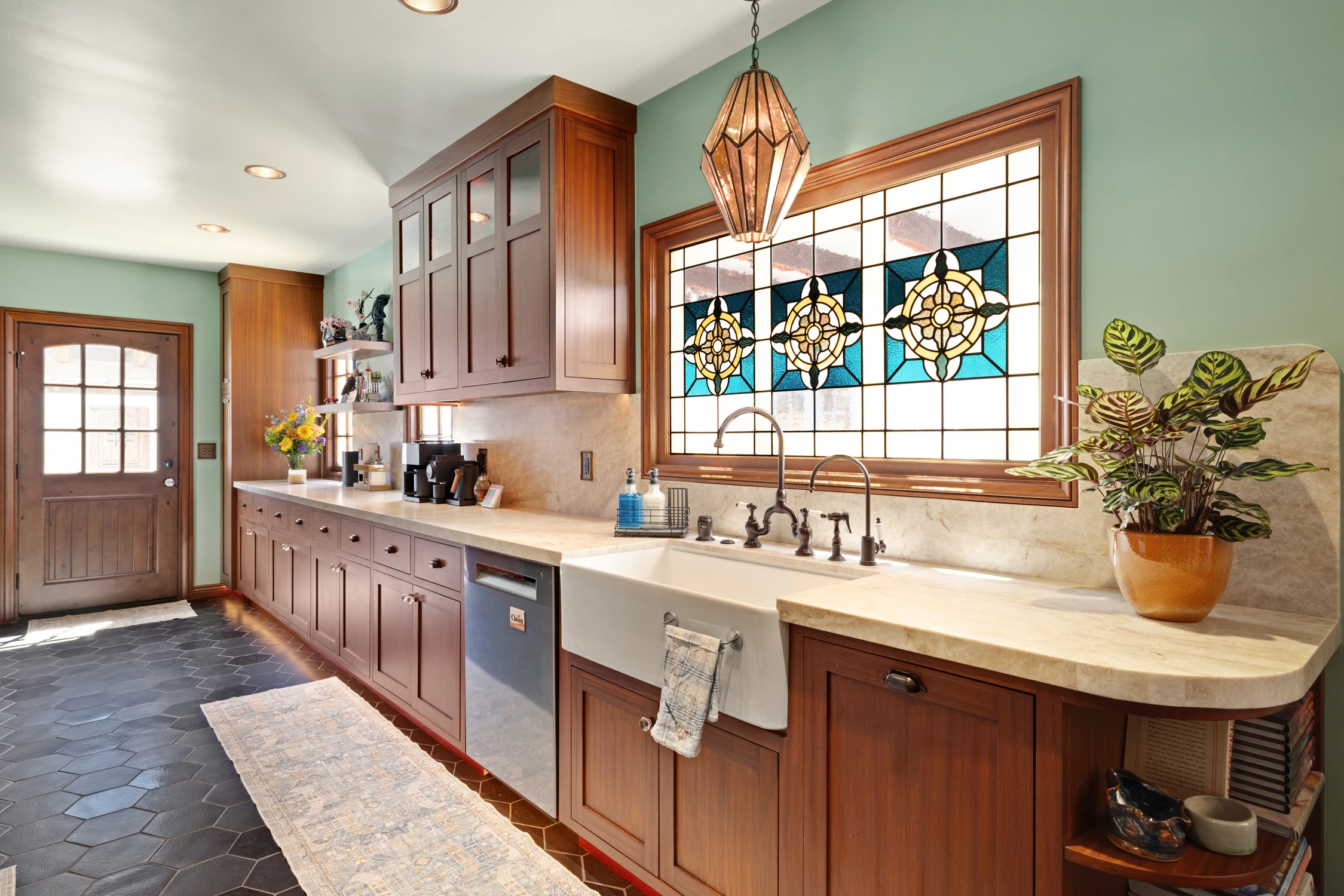 Kitchen sink beneath stained-glass window with warm wood cabinetry
