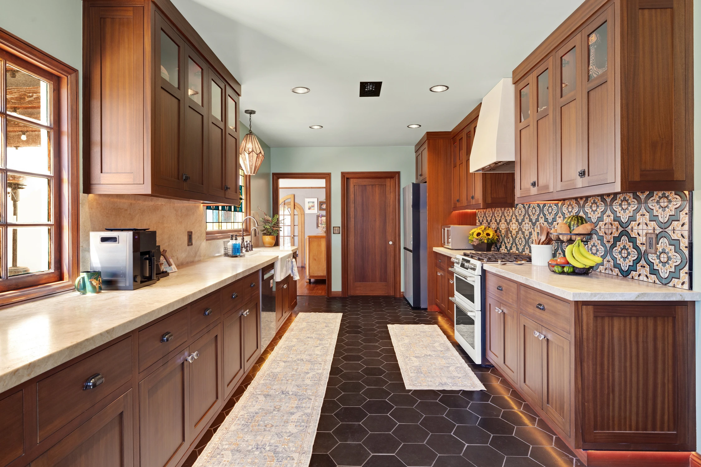 Kitchen work aisle with wood cabinets, dark floor tile, and patterned backsplash