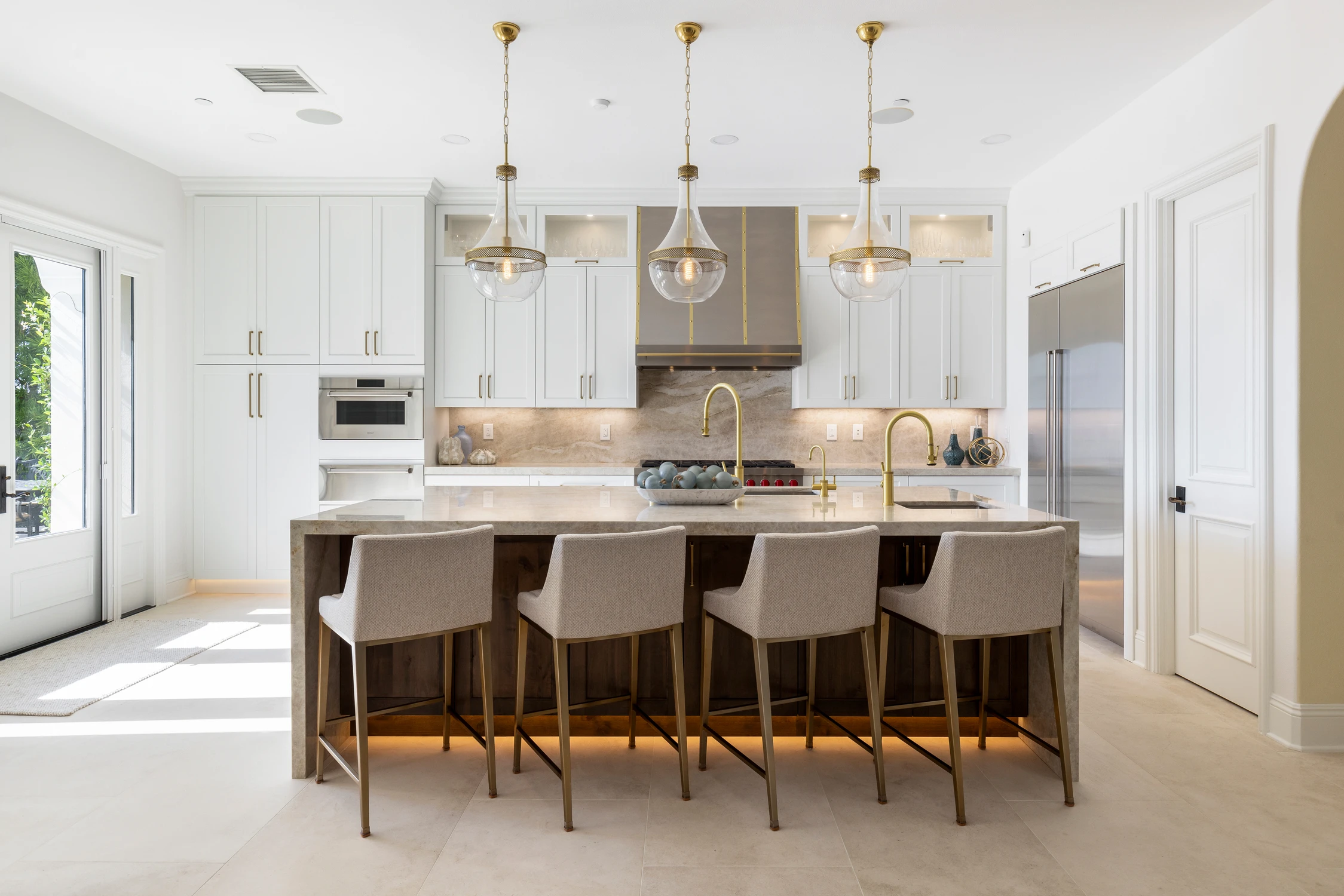 White kitchen with wood island, brass pendants, and ocean view