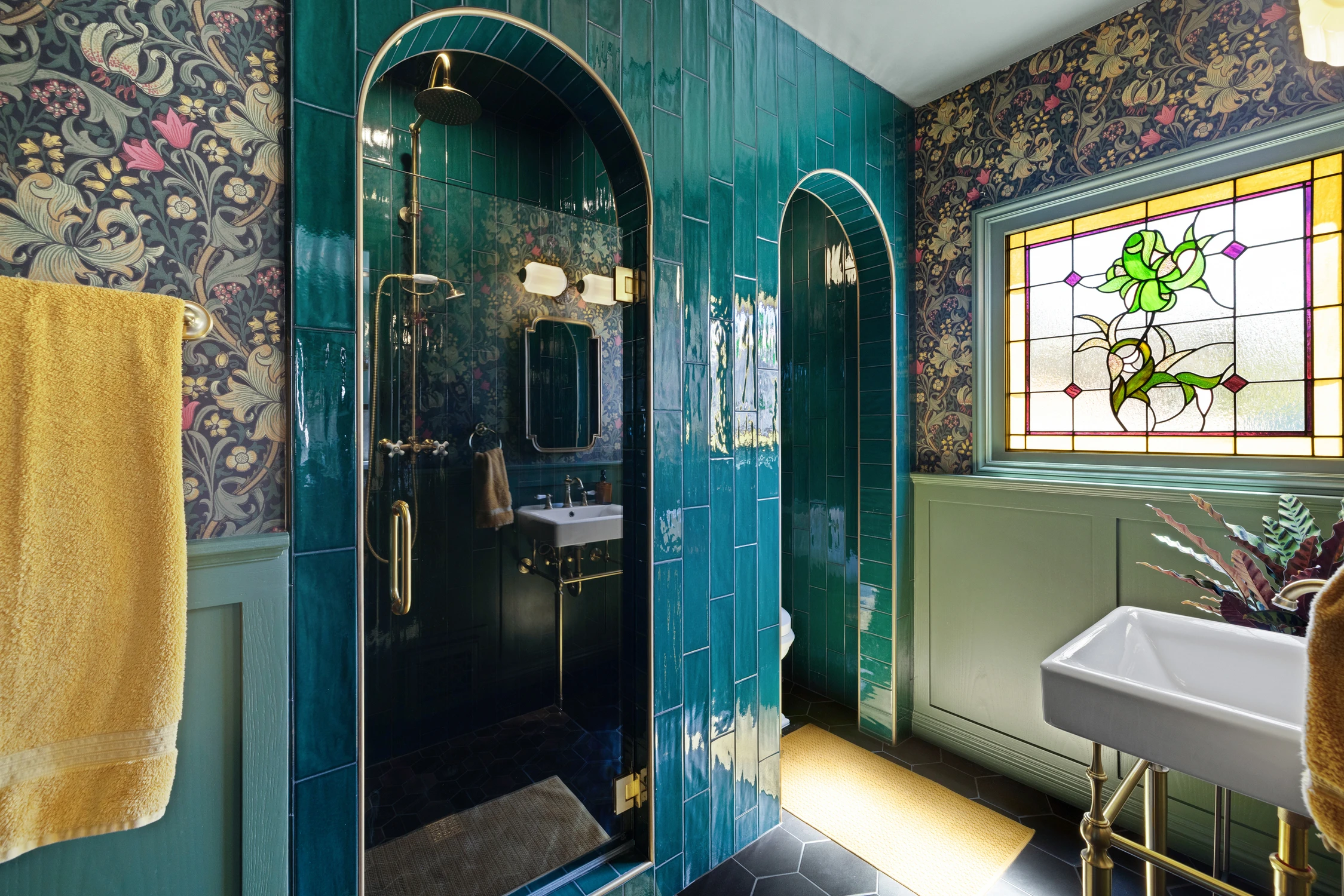 Bathroom with deep green tile shower, floral wallpaper, and stained-glass window