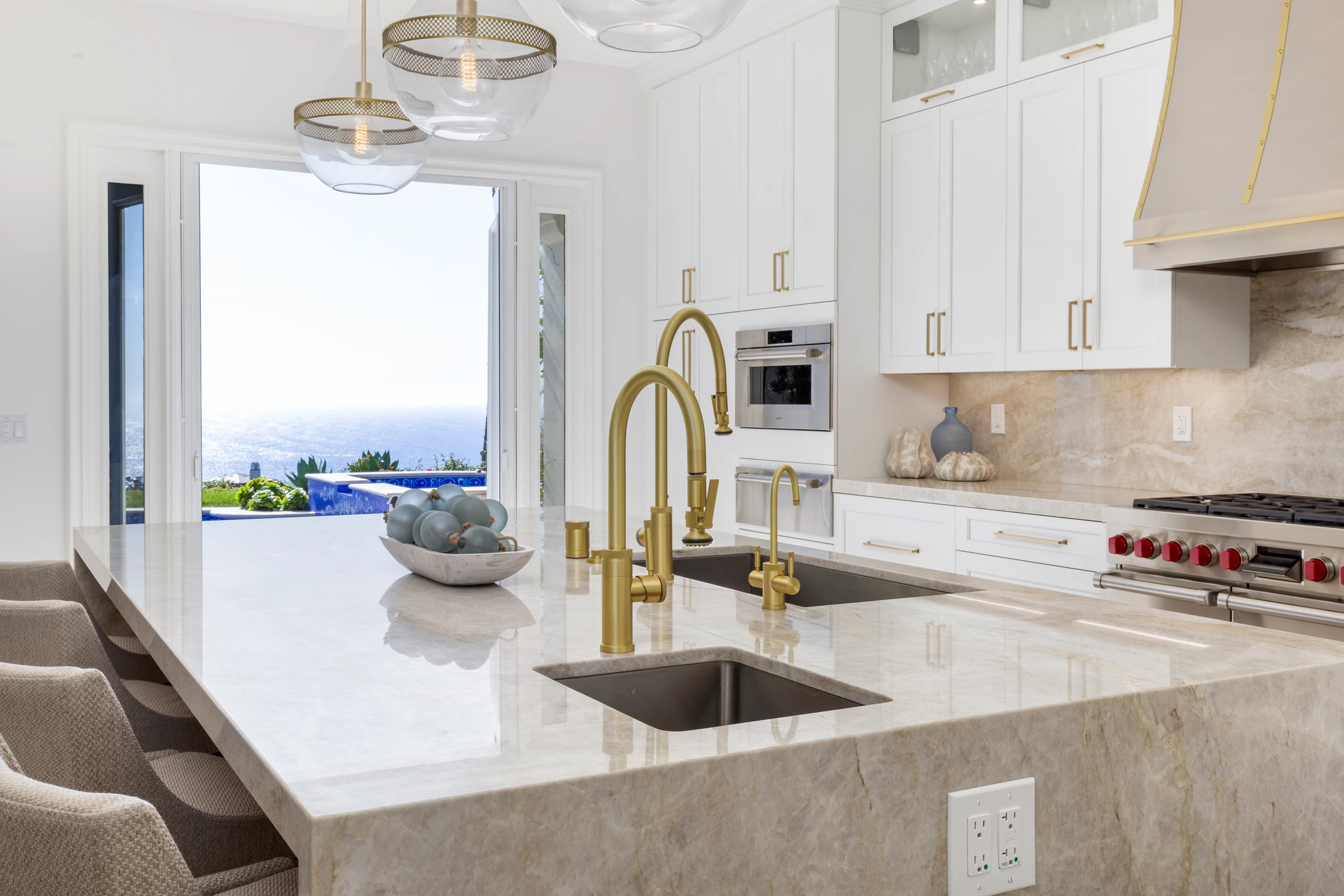 Kitchen island with white stone counter, brass faucet, and water view