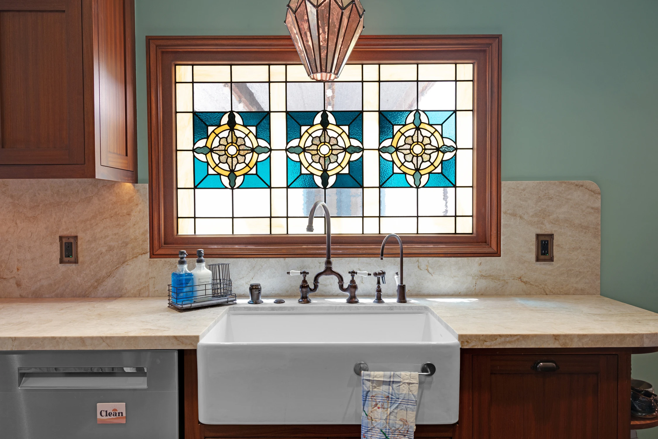 Kitchen sink below stained glass with dark gooseneck faucet
