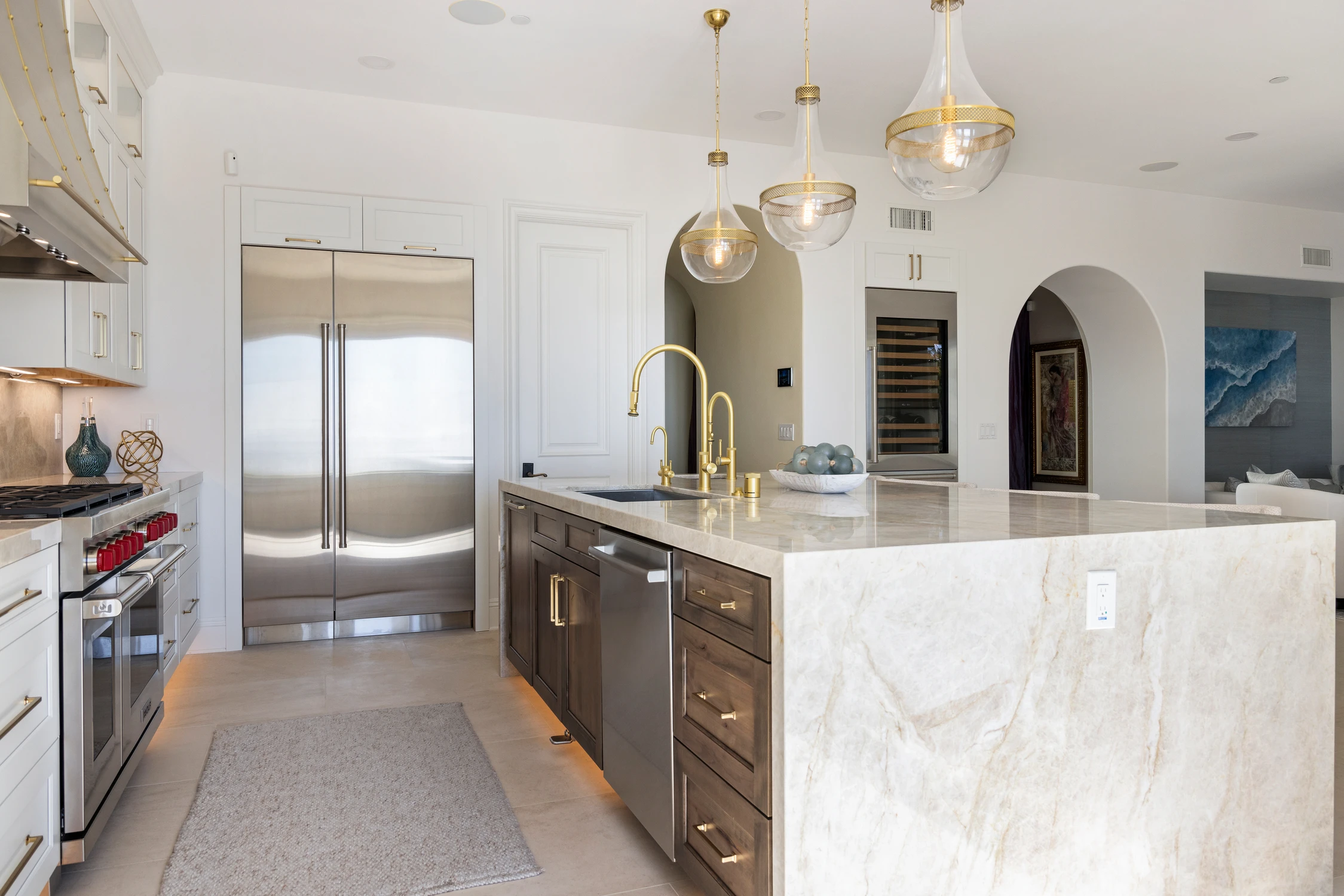 Kitchen island with brass faucet, wood drawers, and white stone counter